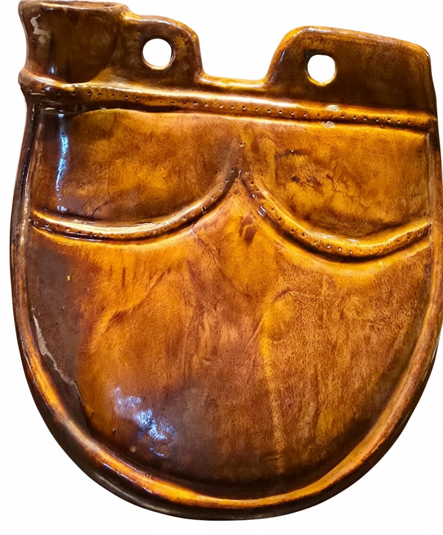 Vintage Glazed Ceramic Wall Pocket Planter: A vintage glazed ceramic wall pocket planter, featuring a rich mottled brown and amber glaze. The planter is designed to resemble a satchel or pouch, with decorative raised lines and two holes at the 