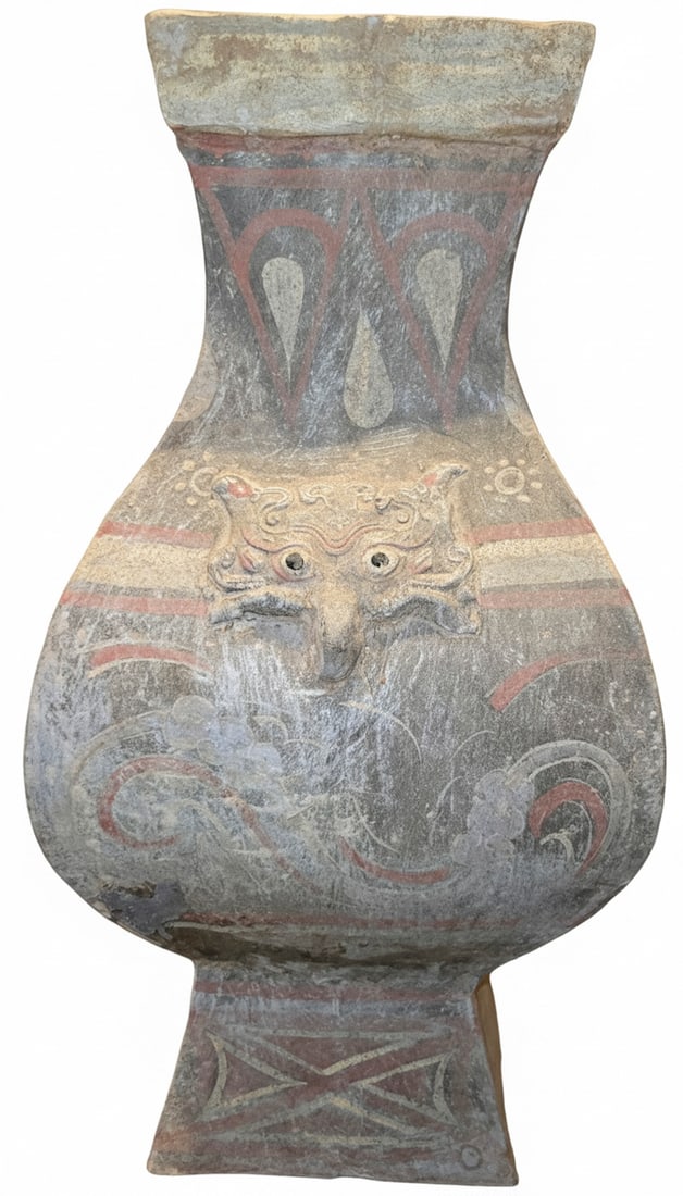 Chinese Han Dynasty Painted Grey Pottery Hu-Form Vase: A Chinese Han Dynasty (206 BC - 220 AD) grey pottery hu-form vase, featuring hand-painted decorations in red, white, and black pigments. The vase is adorned with a molded taotie mask motif on two side