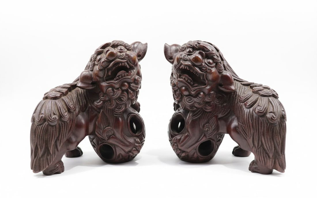 Pair of Carved Wooden Foo Dog Bookends: A pair of intricately carved wooden Foo Dog bookends, depicting the traditional Chinese guardian lions with detailed manes and fierce expressions. The wood has a rich, dark reddish-brown patina. Each 