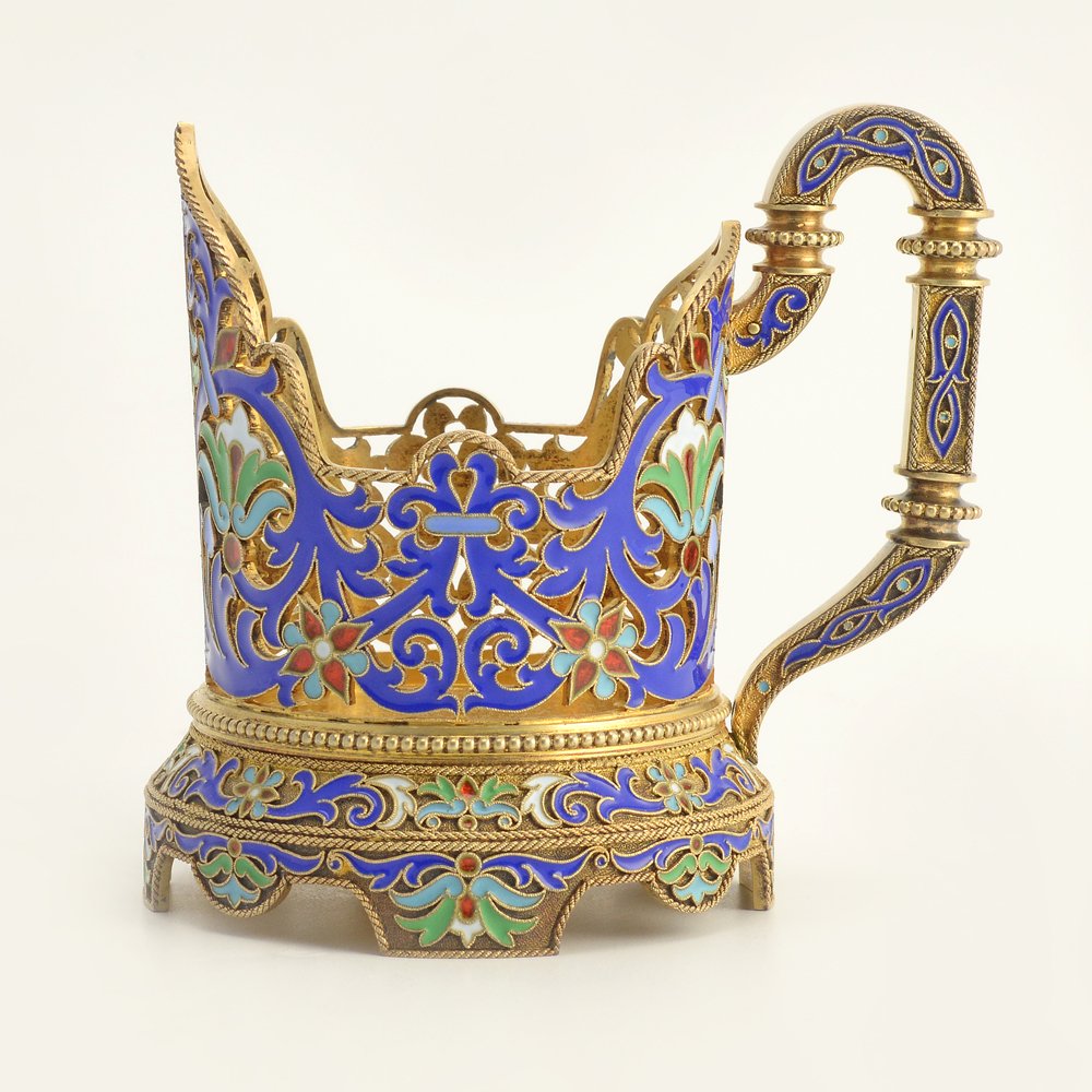 A Russian silver & cloisonne enamel tea glass holder: A Russian gilded silver and cloisonne enamel tea glass holder, Grachev, St Petersburg, circa 1895. Cylindrical form on shaped foot with arched prow, the pierced silver body decorated in shades of brig