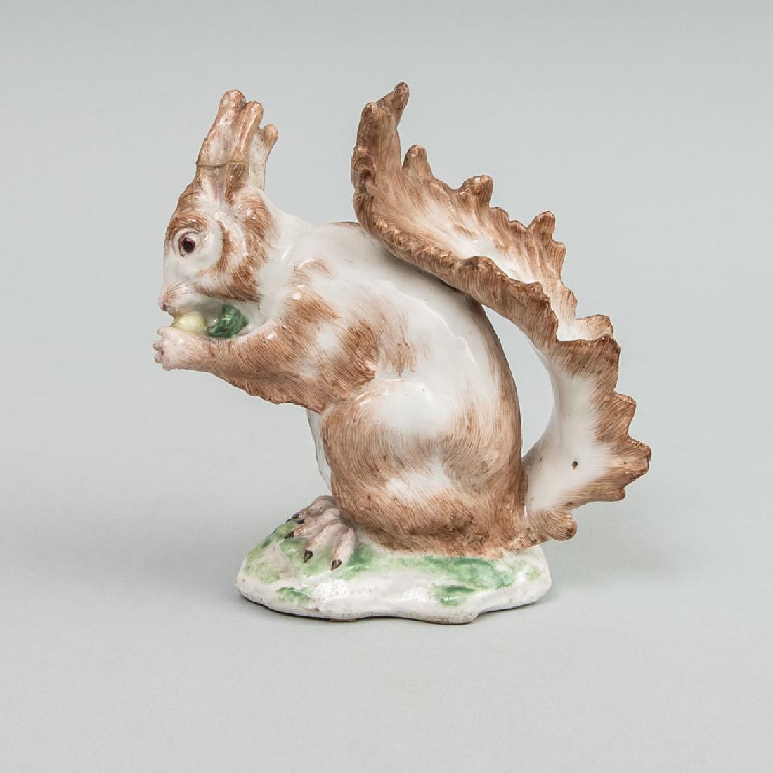 English Porcelain Model of a Squirrel Eating a Nut: English Porcelain Model of a Squirrel Eating a Nut Possibly redecorated and with an added gold anchor, with labels 'Chelsea 1755 JM ARM Xmas '64' and 'AP. Co. N.Y.'5 in. high. Collection of Abby Rocke