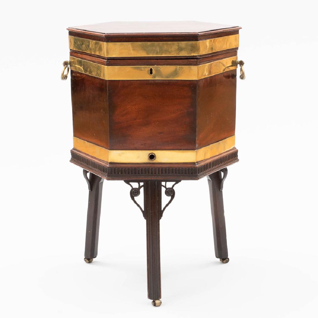 George III Brass-Mounted Mahogany Hexagonal Cellarette: George III Brass-Mounted Mahogany Hexagonal Cellarette The hinged top opening to a fitted interior, raised on a fluted frieze on molded legs and casters. 29 3/4 x 17 x 17 in. Property from the Reposit