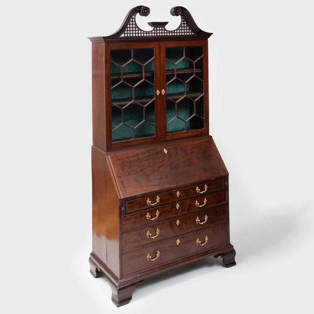 George III Mahogany Slant-Front Bookcase: George III Mahogany Slant-Front Bookcase In the Chippendale taste; with a pair of glazed cabinet doors enclosing two shelves with silk moiré back panel, above the slant-front with a baise-lined
