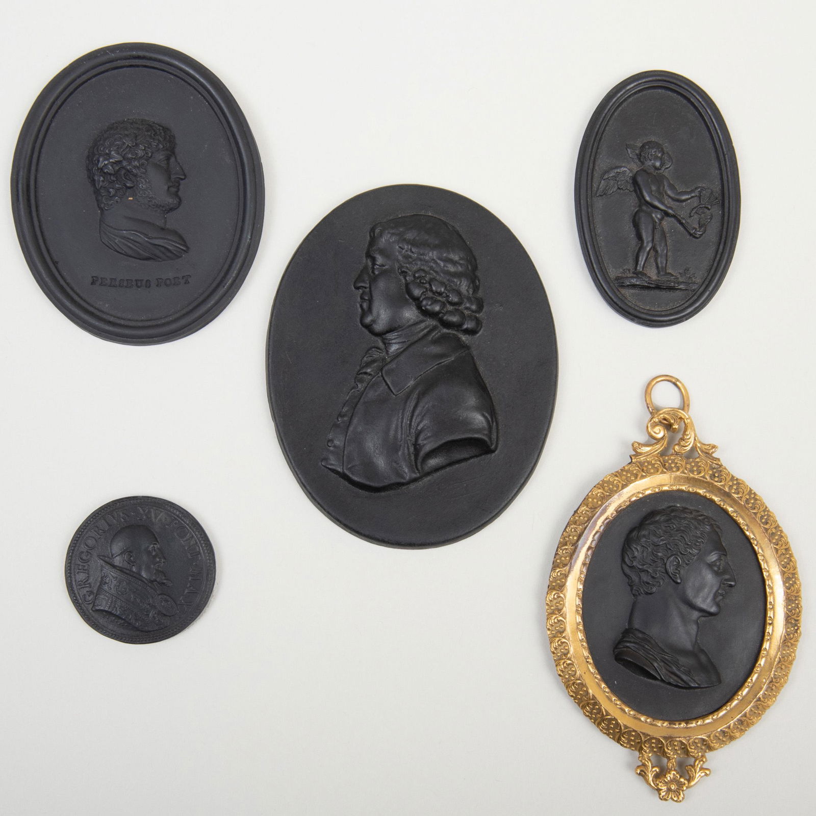 Five Wedgwood Black Basalt Small Medallions: Five Wedgwood Black Basalt Small Medallions Three with impressed lowercase mark for Wedgwood & Bentley, two apparently unmarked. The largest 3 3/8 in. high. The cupid with label for the O'Byrne Collec