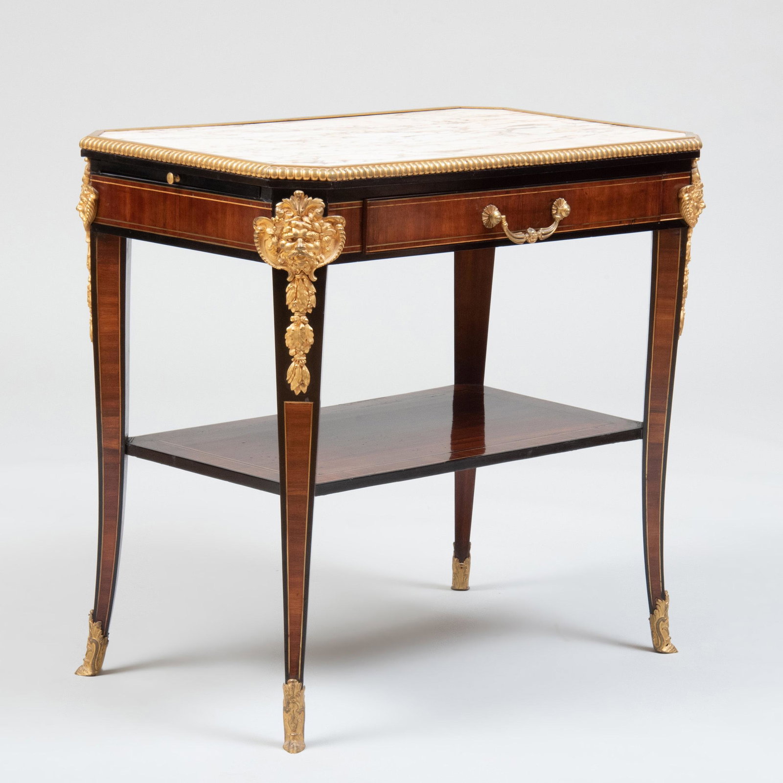Napoleon III Ormolu and Brass-Mounted Mahogany and: Napoleon III Ormolu and Brass-Mounted Mahogany and Ebonized Side Table Fitted with an ormolu-mounted marble top, flanked by candle slides, above one drawer and a shelf, raised on splayed legs headed b