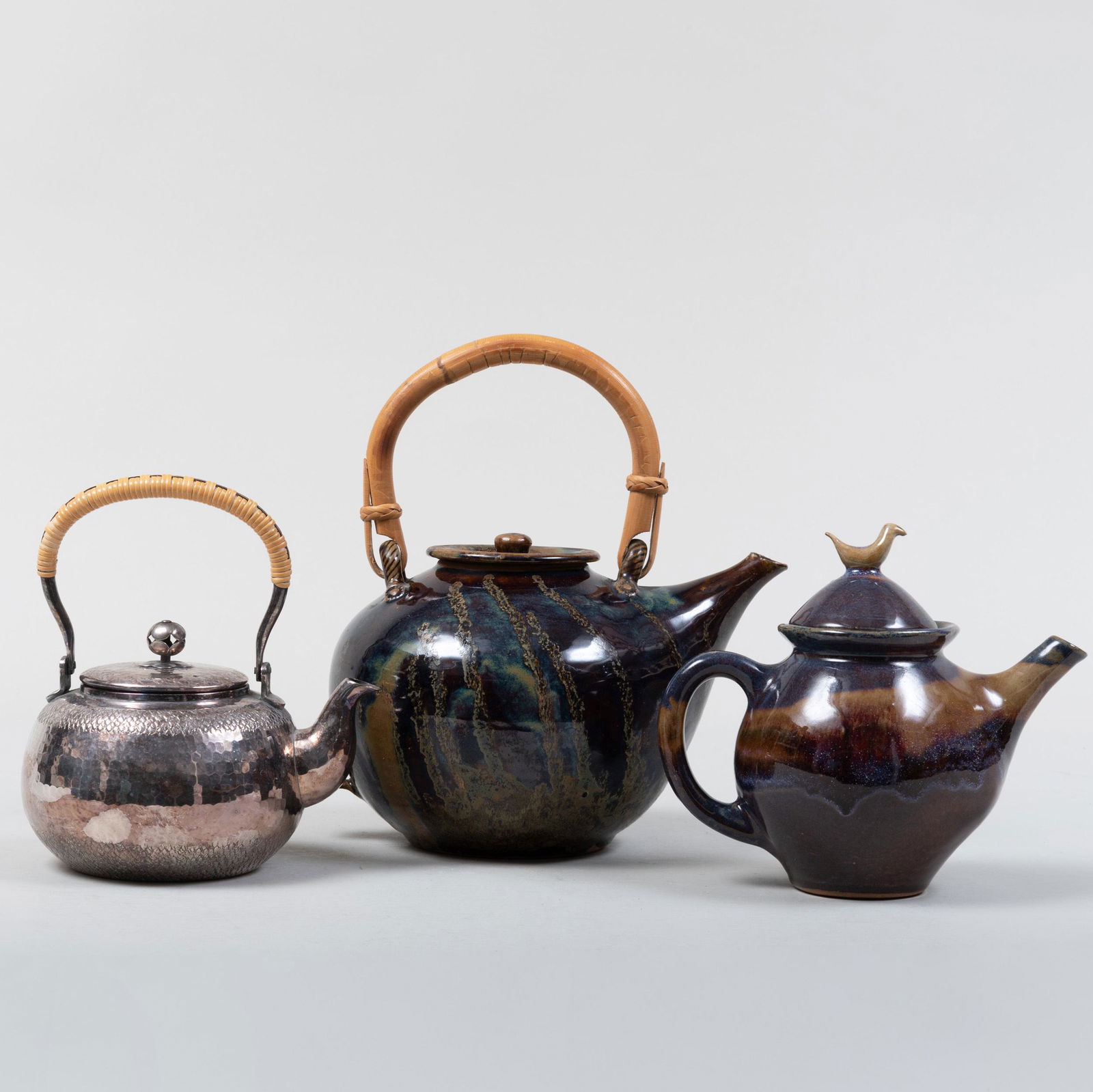 Two Studio Pottery Glazed Earthenware Teapots and a: Two Studio Pottery Glazed Earthenware Teapots and a Japanese Silver Metal Teapot The largest 9 1/4 in. wide (over handle). Property of a Lady from a Berkshire Home Designed by Bunny Williams