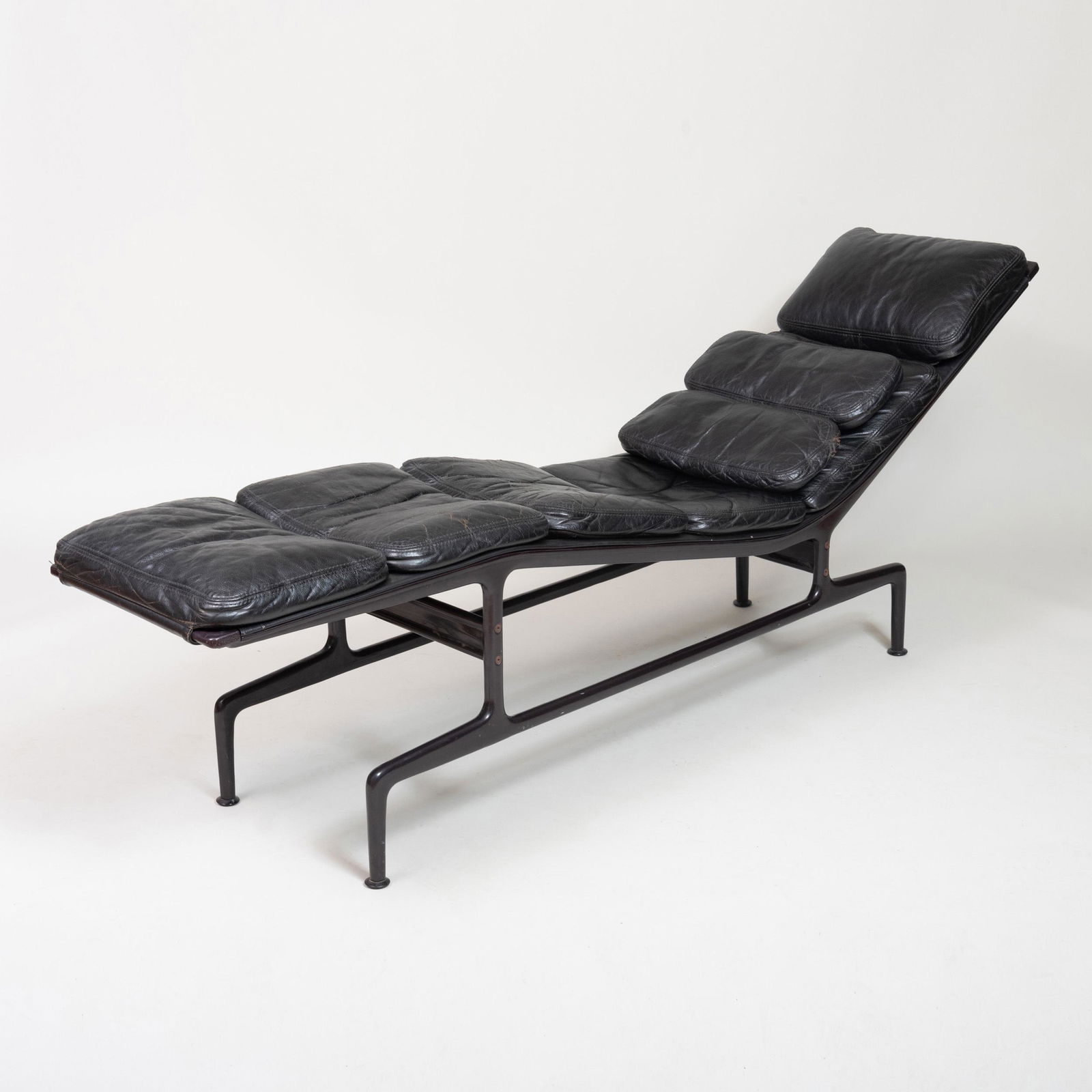 Eames Coated Metal and Leather 'Billy Wilder' Chaise: Eames Coated Metal and Leather 'Billy Wilder' Chaise With two loose cushions. 28 1/2 in. x 6 ft. 2 in. x 17 in. Note: Film director Billy Wilder was known to take naps on sawhorses while on set. A fr