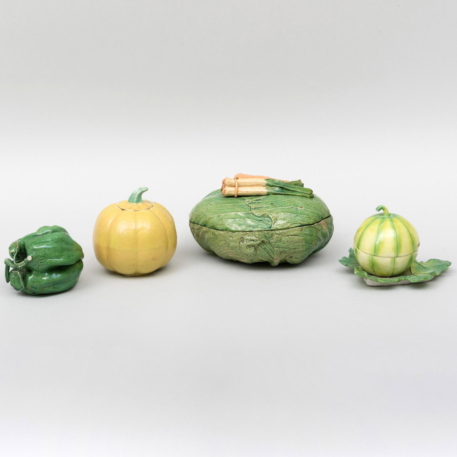 Group of Four Earthenware and Porcelain Vegetable Form: Group of Four Earthenware and Porcelain Vegetable Form Table Ornaments Comprising: A lettuce form box with leek and carrot finial A Portuguese model of a pepper A yellow glazed gourd form box and cove