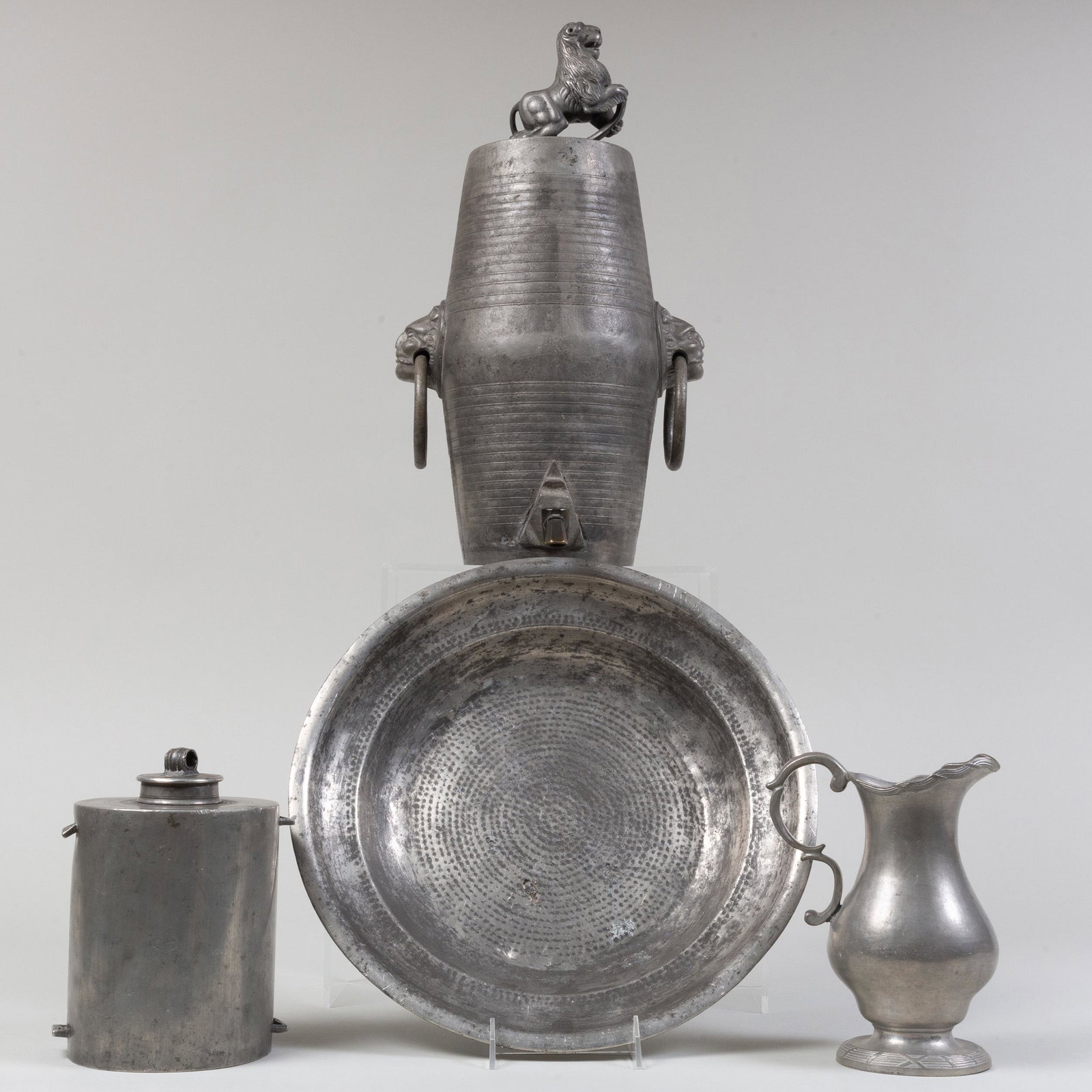 Three Pewter Vessels and a Charger: Three Pewter Vessels and a Charger Comprising: A baroque style cistern with lion finial A pitcher, attributed to