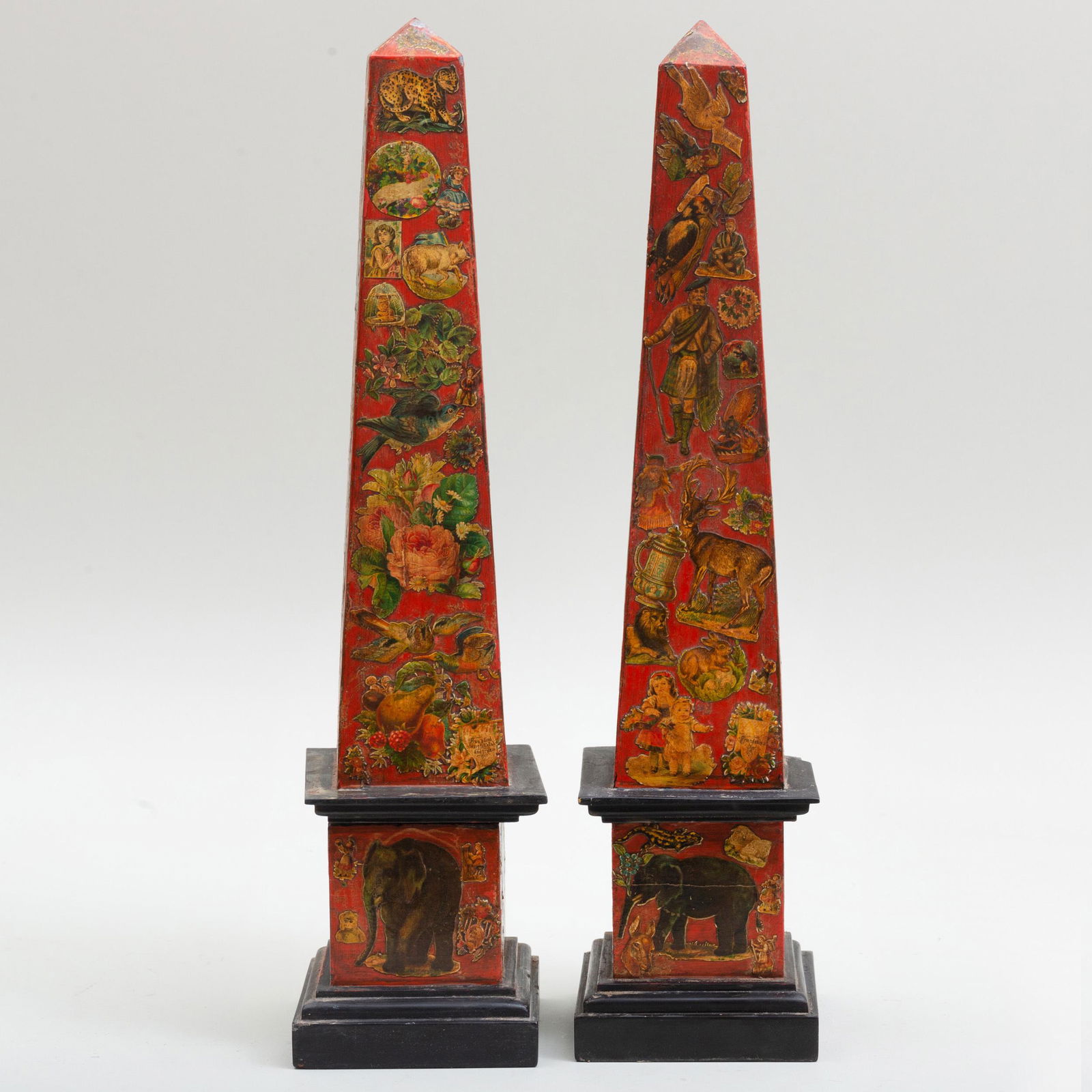 Pair of Decalcomania Decorated Red Painted Stone: Pair of Decalcomania Decorated Red Painted Stone Obelisks 19 x 4 1/2 x 4 1/2 in. Applied paper label for William Griffith Antiques.