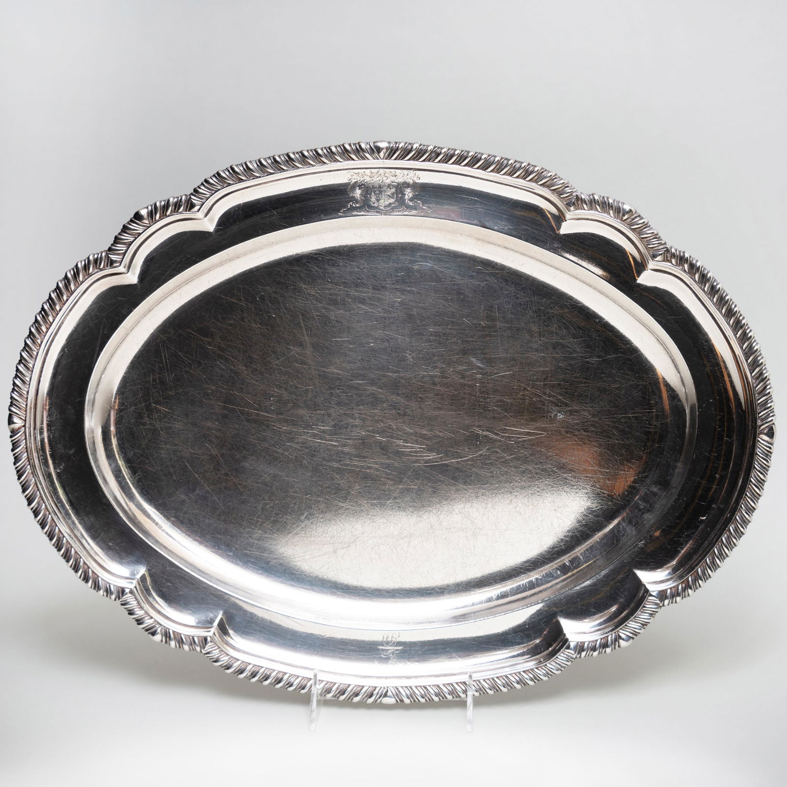George III Silver Platter: George III Silver Platter Mark of William Bennett, London, 1817; engraved with two heraldic devices. 18 in. wide, 62.6 oz. approx. weight. Sold Stair Galleries, March 10, 2012, Lot 908.