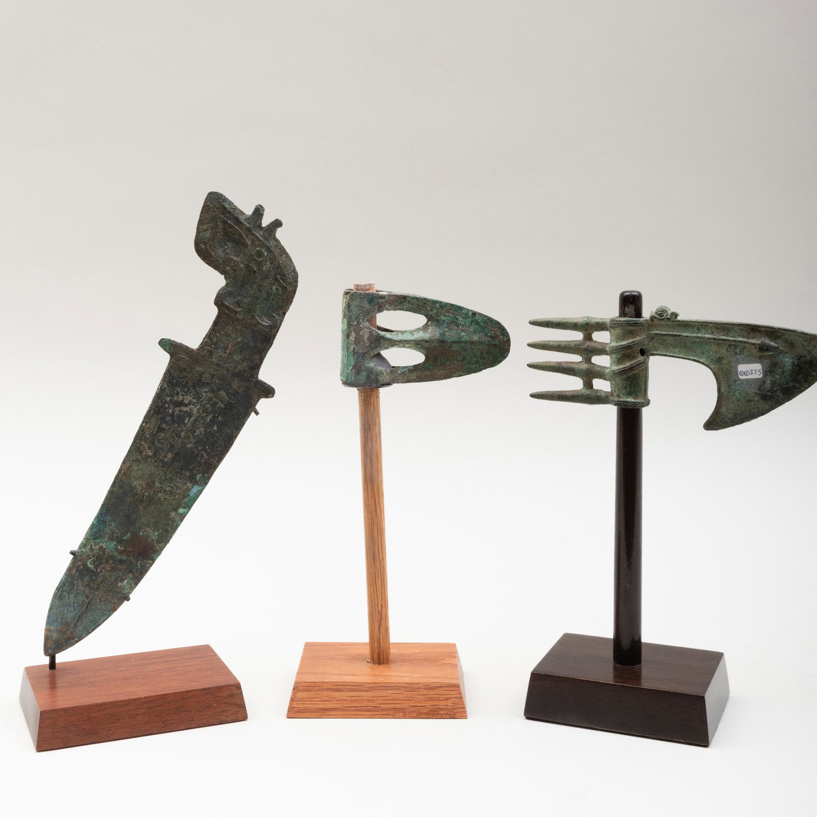 Luristan Bronze Axe Blade, a Luristan Bronze Slotted: Luristan Bronze Axe Blade, a Luristan Bronze Slotted Axe, and a Chinese Western Zhou Dynasty Dagger with Decorated Handle Each raised on stands. The axe blade 9 3/4 x 7 x 3 in. (overall), the slotted 