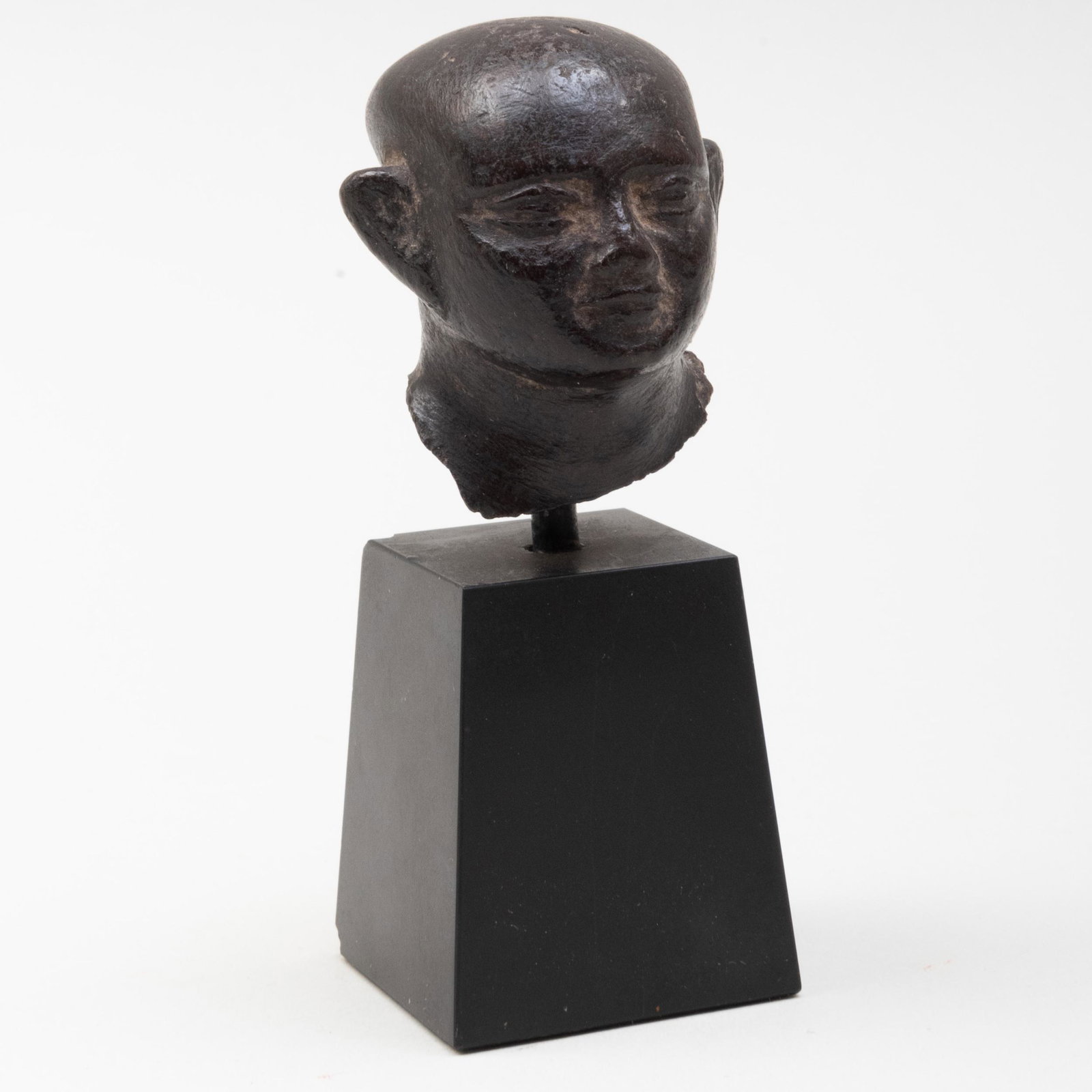 Egyptian Basalt Head of a Man: Egyptian Basalt Head of a Man Raised on stand. The head 1 7/8 x 1 1/2 x 1 3/4 in. Property from the Estate of William Kelly Simpson