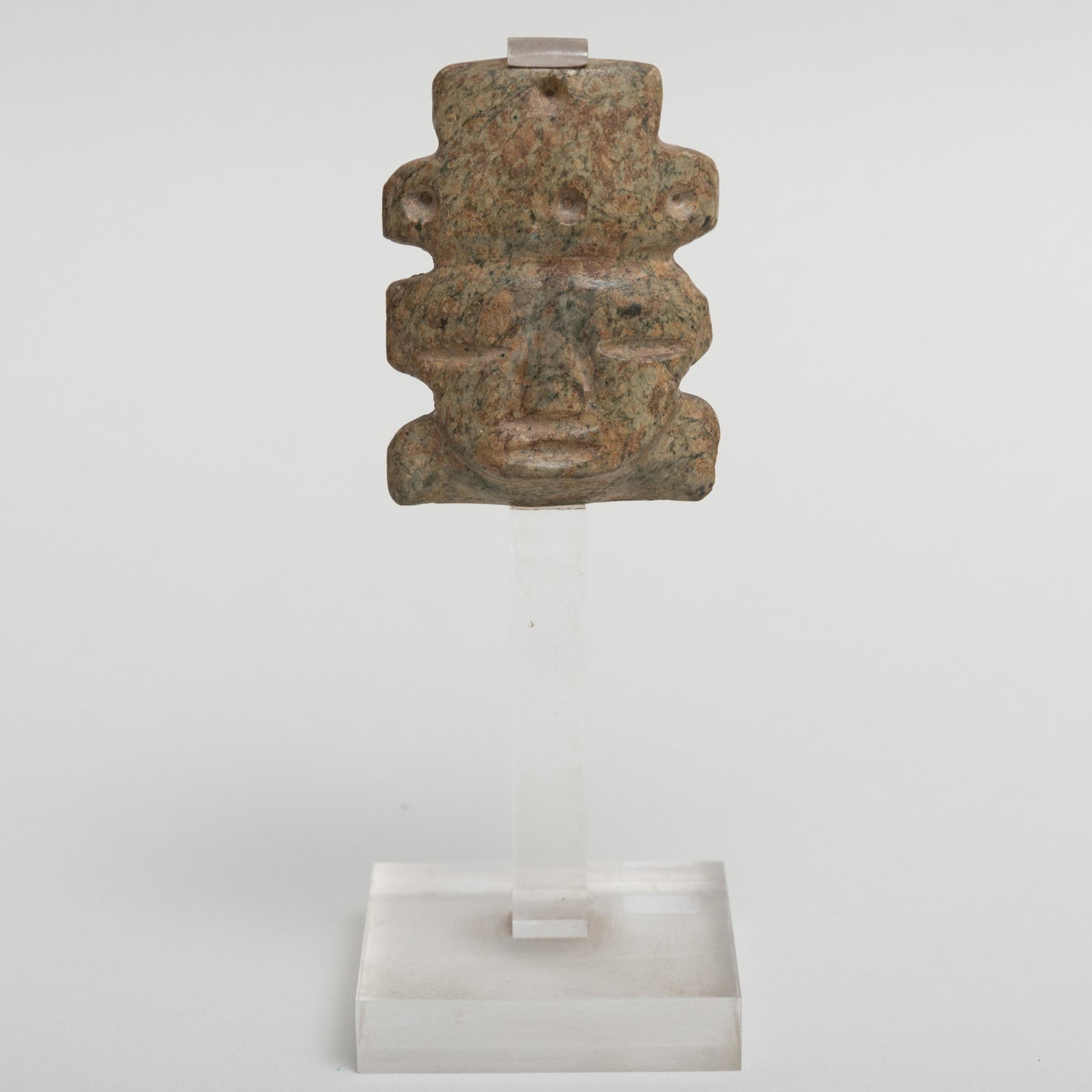 Pre-Colombina Carved Stone Mask, Mezcala, West Mexico: Pre-Colombina Carved Stone Mask, Mezcala, West Mexico Raised on stand; together with a Pre-Columbian Metal Pendant. The mask 2 3/4 x 2 in., 6 1/4 in. high (overall), the pendant 3 3/4 in. diam., (2 pc