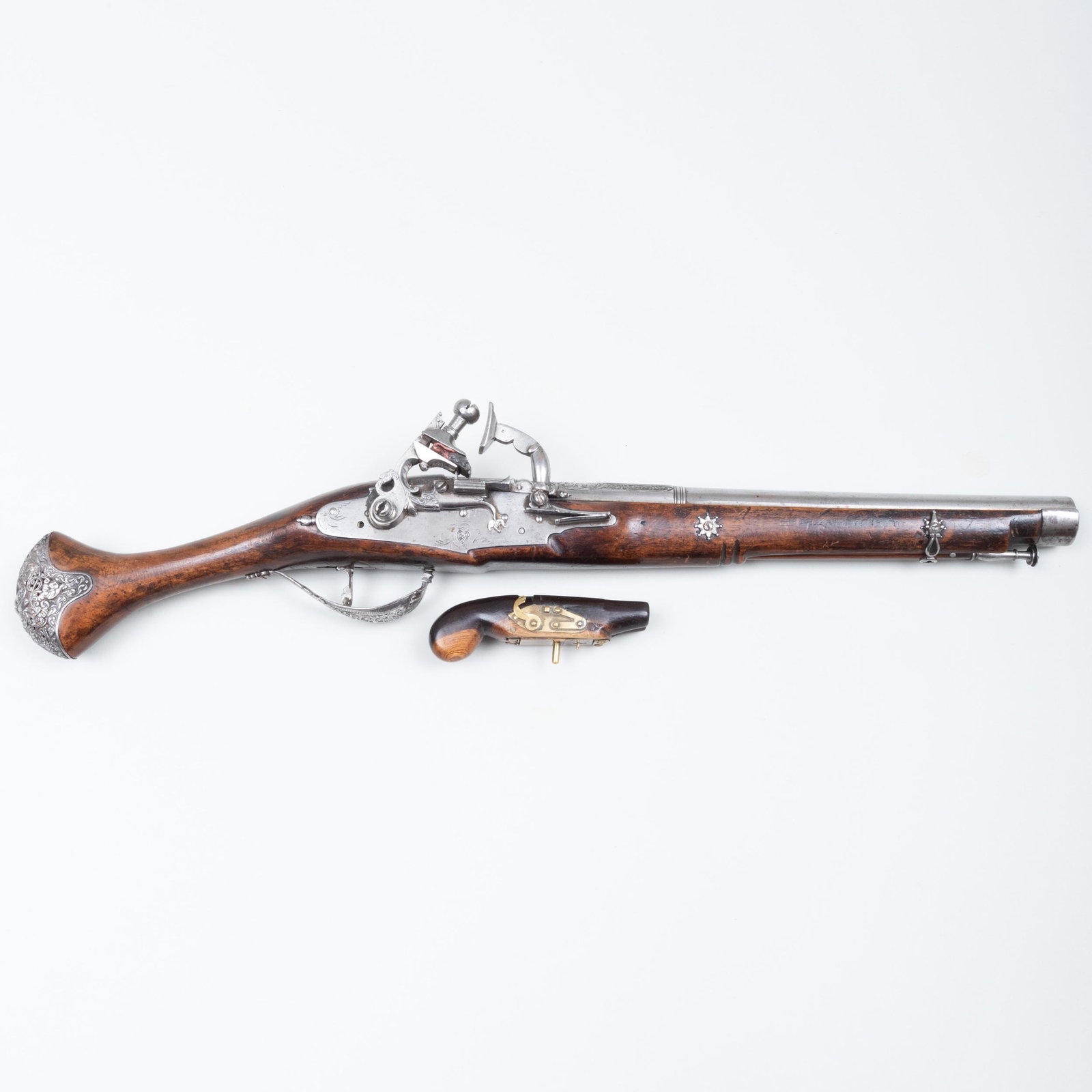 Silver Metal-Mounted Flint Lock Pistol and a Treen: Silver Metal-Mounted Flint Lock Pistol and a Treen Pistol Form Snuff Box The pistol 21 1/2 in. long, the snuff box 4 1/4 in. long.