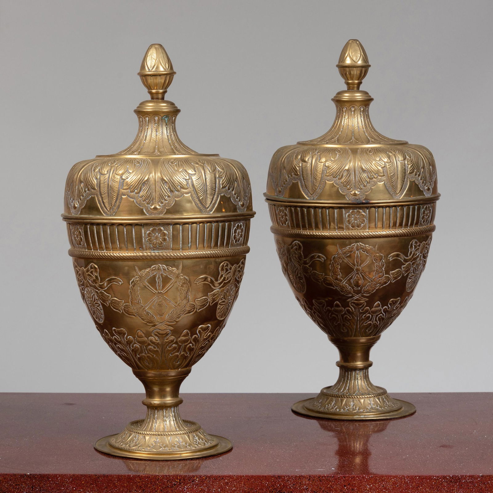 Pair of Continental Brass Repoussé Urns and Covers: Pair of Continental Brass Repoussé Urns and Covers Raised on an ebonized plinth base. 28 1/2 x 12 1/2 in. diam. (overall). John Richardson: A Scholar Collects