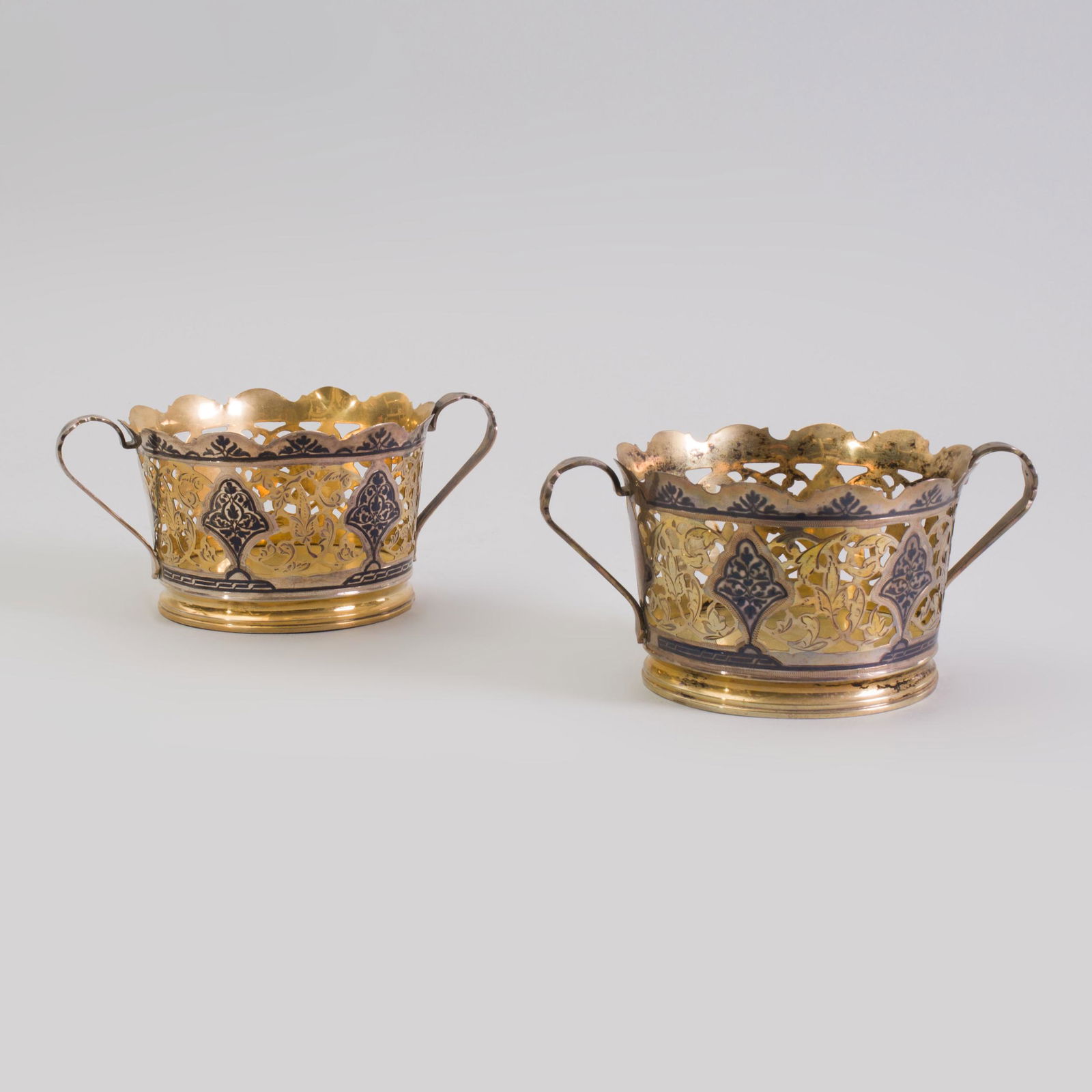 Pair of Russian Silver-Gilt and Niello Bottle Coasters: Pair of Russian Silver-Gilt and Niello Bottle Coasters Marked '875' with five-pointed star; after 1958. 3 1/4 x 7 in. over handles, approx. 15 oz. Selected Property from the Collection of Mr. and Mrs.