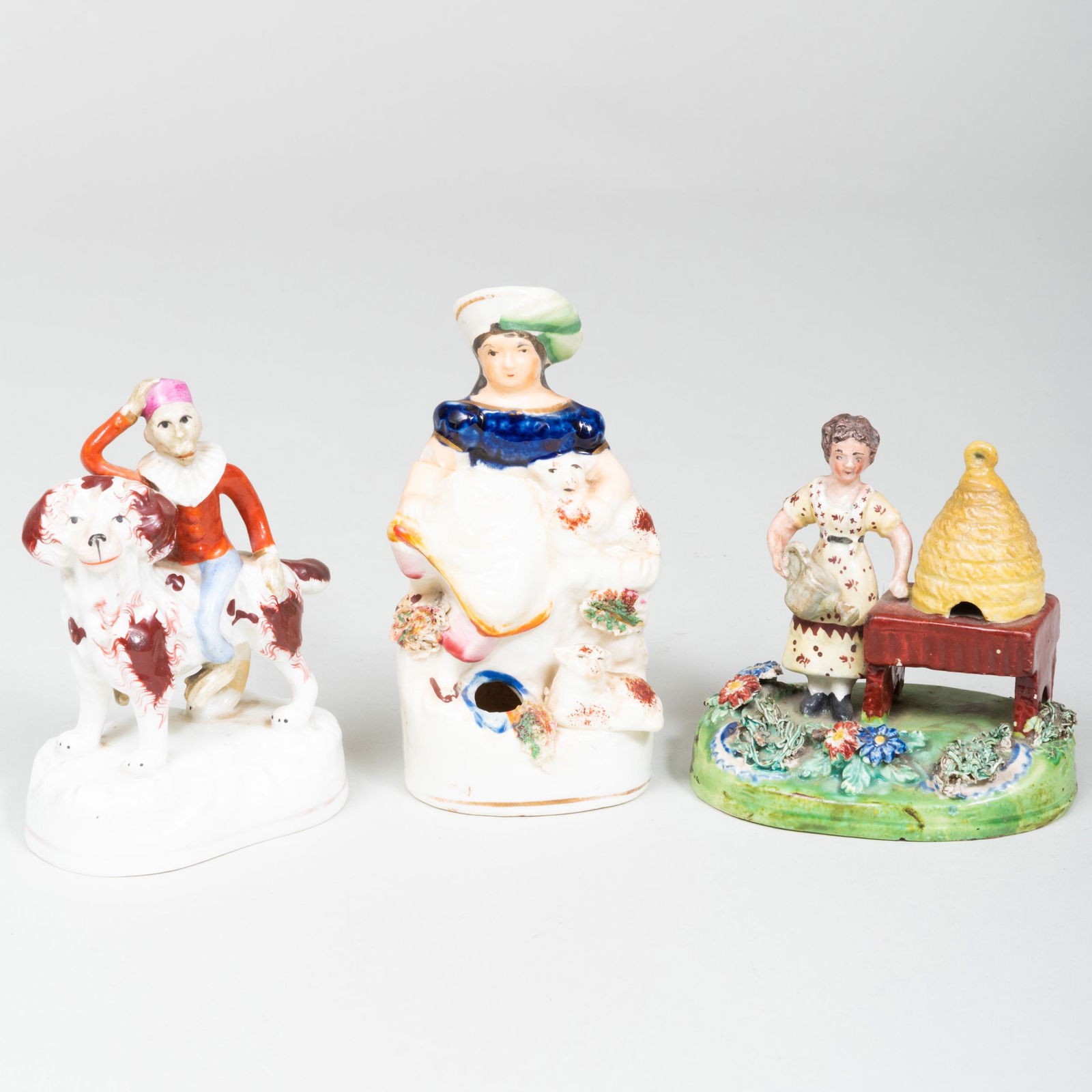 Group of Three Staffordshire Figural Groups: Group of Three Staffordshire Figural Groups Comprising: A figure of a female bee keeper A monkey riding a dog A shepherdess form inkwell The largest 5 in. high.