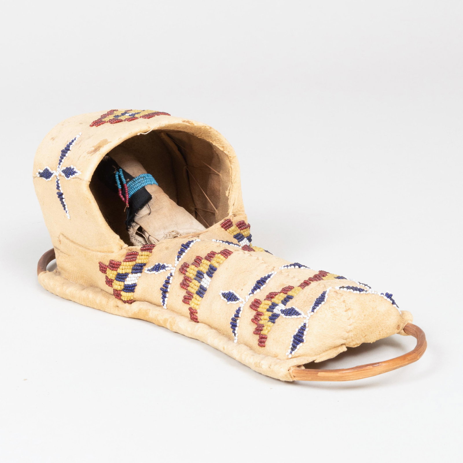 Apache Beaded Hide, Cloth and Reed Model of a: Apache Beaded Hide, Cloth and Reed Model of a Cradleboard with Doll, Probably Southern Plains 11 in. in length. Property from the Estate of Martin and Faith-Dorian Wright