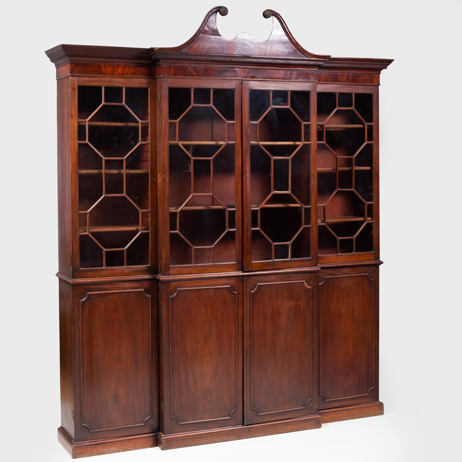 George III Mahogany Breakfront Bookcase: George III Mahogany Breakfront Bookcase In three parts. The upper glazed section fitted with shelves, above the cabinet doors opening to drawers, raised on a plinth base. 7 ft. 8 in. x 6 ft. in. x 14 