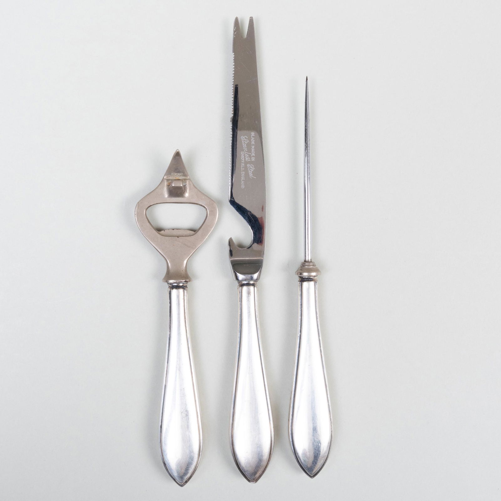 Three Cartier Silver Bar Utensils: Three Cartier Silver Bar Utensils Marked 'Sterling'. Comprising: A citrus knife with steel blades and filled handles An ice pick with steel tine and filled handle A bottle opener with steel key and fi