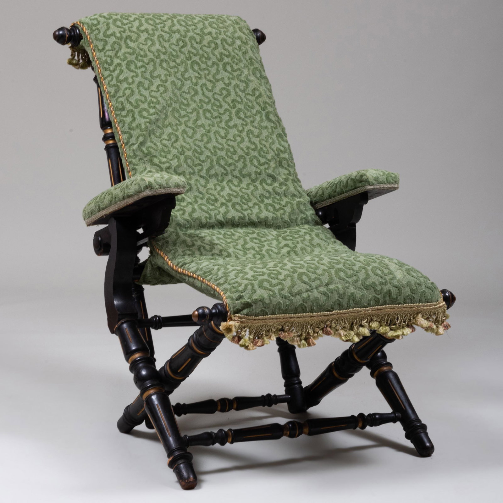 Renaissance Revival Ebonized, Parcel-Gilt and: Renaissance Revival Ebonized, Parcel-Gilt and Upholstered Folding-Reclining Arm Chair, Stamped Hunzinger Stamped Hunzinger N.Y. PAT FEB. 3.1866. 38 1/2 x 25 1/2 x 33 1/2 in. Height of seat 17 in.