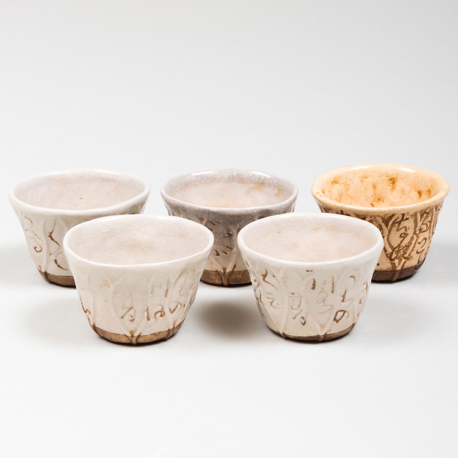 Five Otagaki Rengetsu Glazed Pottery Sencha Tea Cups: Five Otagaki Rengetsu Glazed Pottery Sencha Tea Cups Each incised with a poem in characters; together with wood box inscribed 'Otagaki Rengetsu nun, original box, for five sencha tea bowls'. 1 5/8 x 2