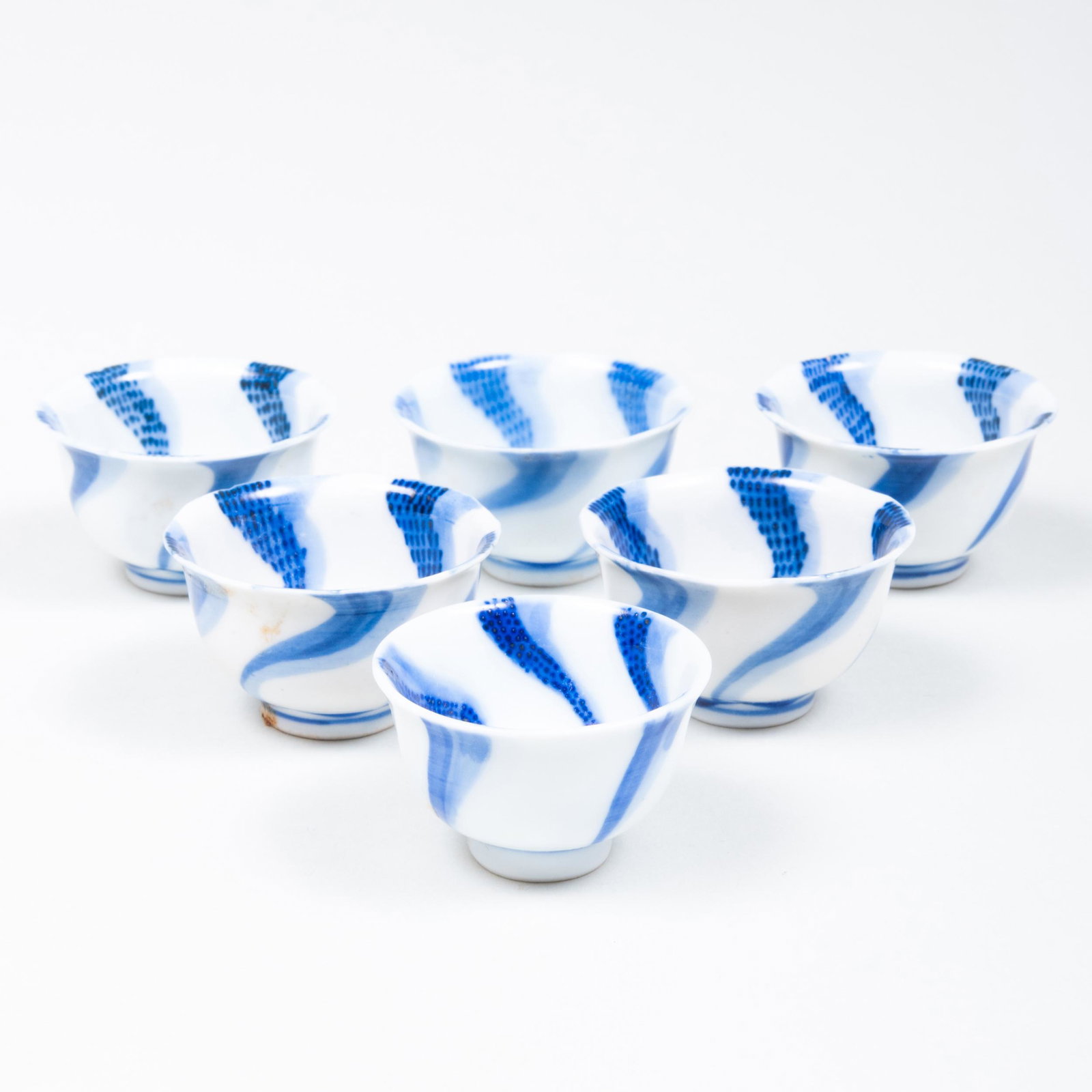 Six Eiraku Blue and White Porcelain Sake Cups: Six Eiraku Blue and White Porcelain Sake Cups Blue six character mark 'Dai Nippon Eiraku zo'; together with associated wood box. 1 1/4 x 2 1/8 in. diam. Tessai-do Co., Ltd., 1991. 