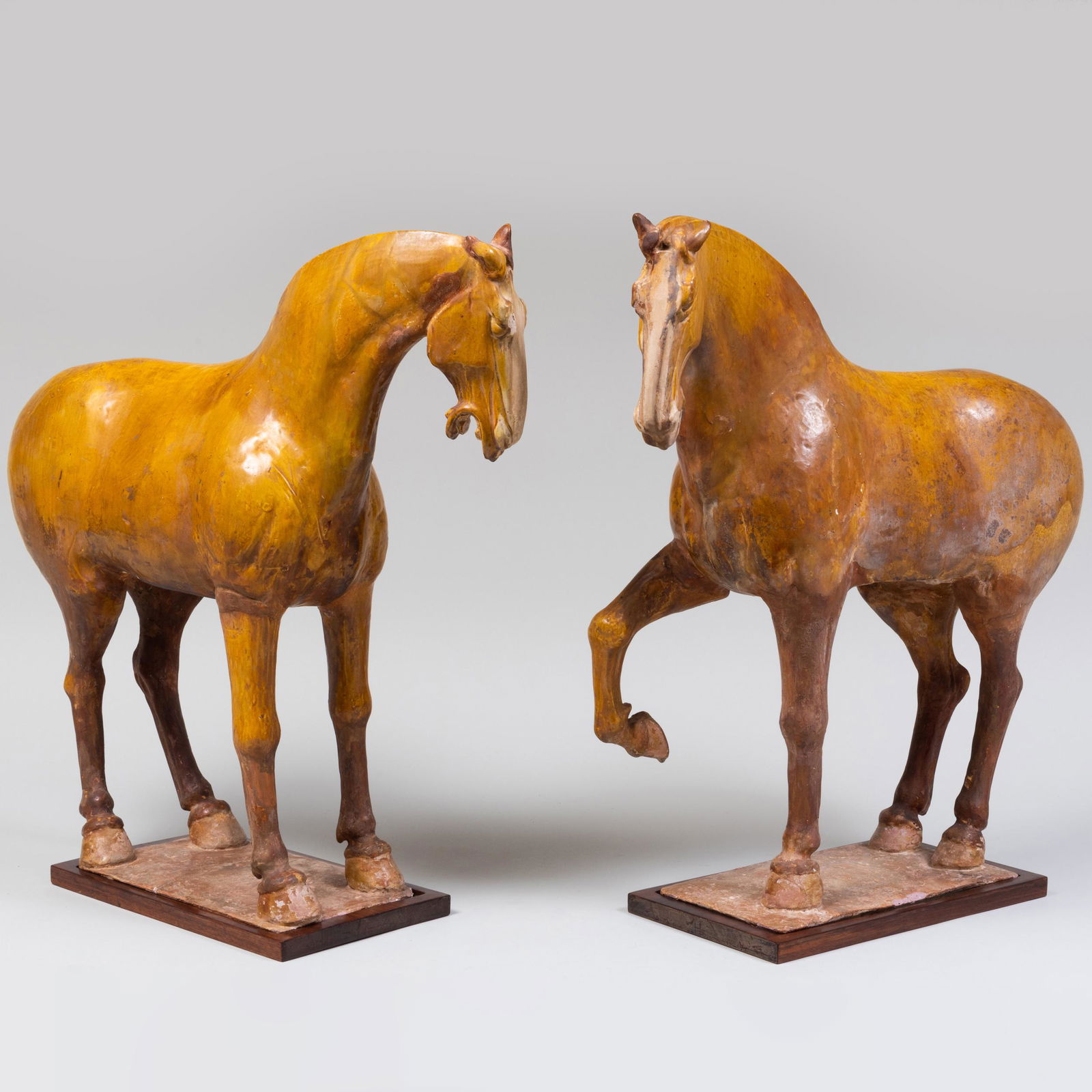 Two Chinese Amber Glazed Pottery Figures of Horses: Two Chinese Amber Glazed Pottery Figures of Horses Together with wood bases. 24 x 22 x 7 in. Property from the Collection of Susan Lasker Brody