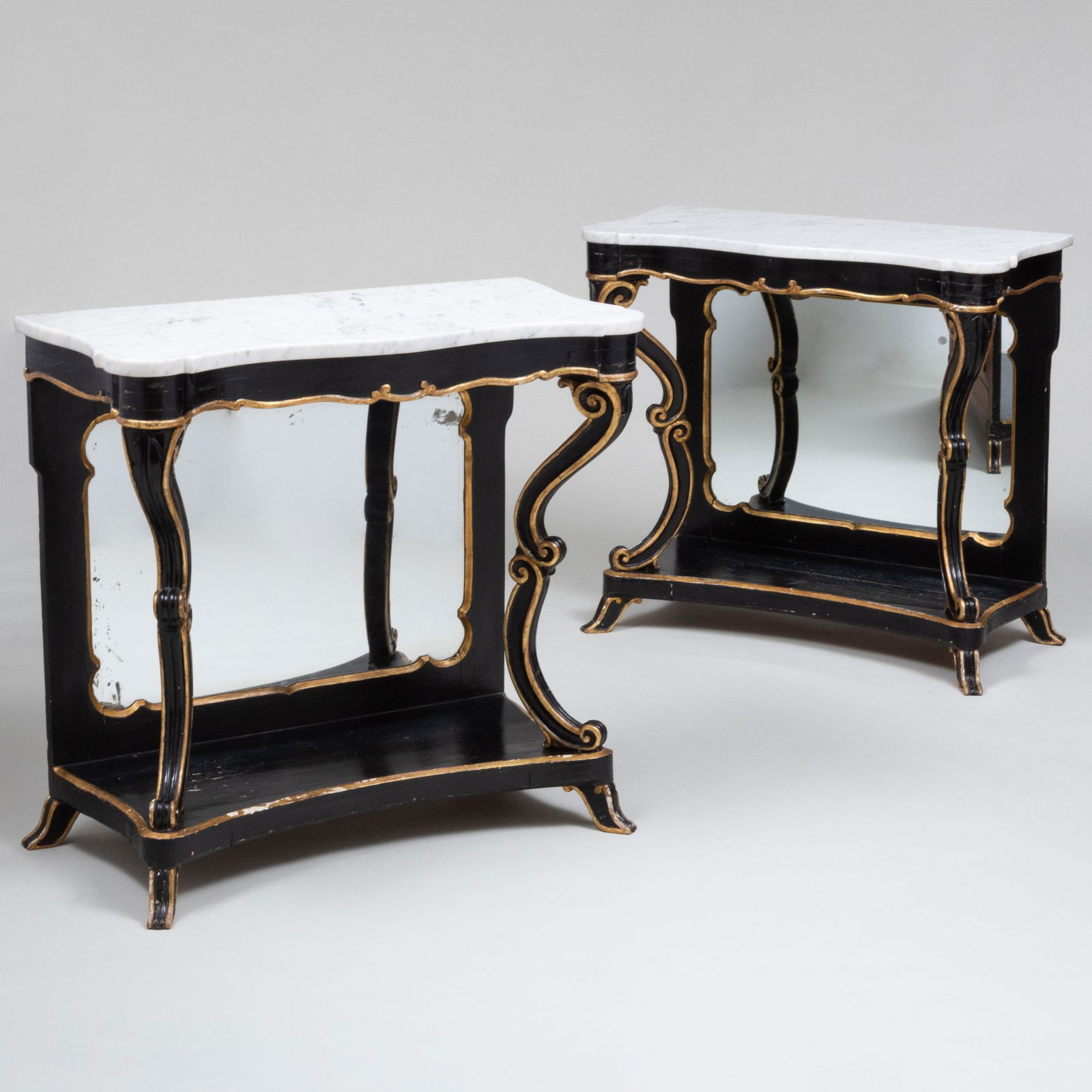 Pair of Italian Ebonized and Parcel-Gilt Console Tables with Marble Tops: Pair of Italian Ebonized and Parcel-Gilt Console Tables with Marble Tops Each fitted with mirrored back panels. 34 x 36 x 17 1/2 in.