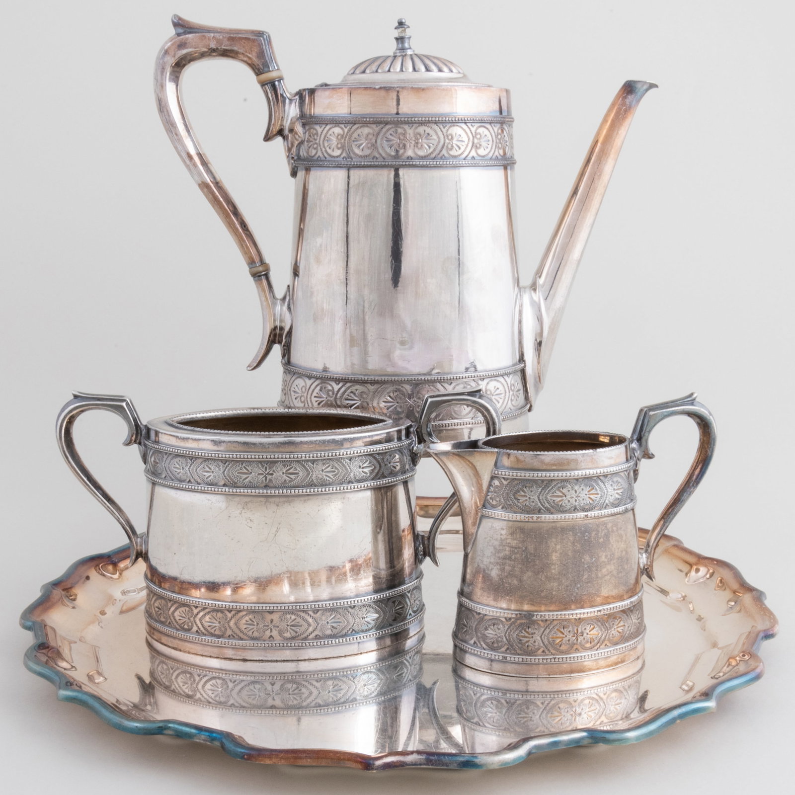 Silver Plate Three Piece Coffee Service and a Salver: Silver Plate Three Piece Coffee Service and a Salver The service comprising: A coffee pot with hinged cover A milk jug A sugar bowl The coffee pot 8 1/2 x 10 1/2 x 3 in., (4 pcs).