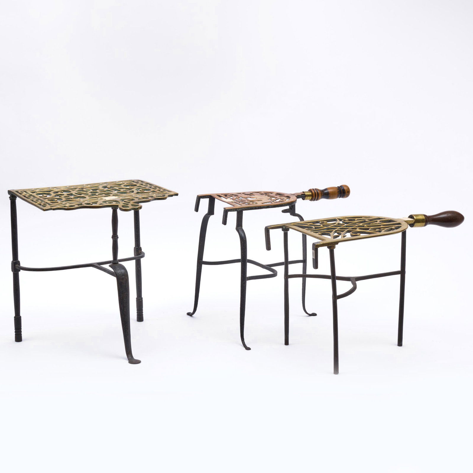 English Gun Metal Trivet and Two Trivets with Turned Wood Handles: English Gun Metal Trivet and Two Trivets with Turned Wood Handles Each raised on iron legs. The gun metal trivet: 13 x 11 1/2 x 13 in. Sold Christie's, South Kensington, The Casmir Collection of Metal