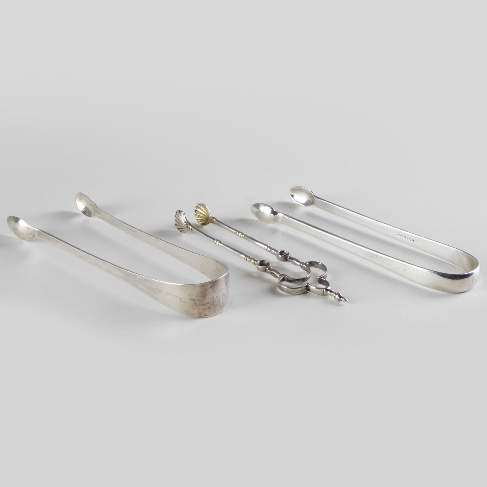 Two Ebenezer Moulton, Boston, Silver Sugar Nips: Two Ebenezer Moulton, Boston, Silver Sugar NipsMaker's mark, monogrammed; together with a pair of nips with shell terminals, indistinctly marked.The largest 6 in. long, 2.9 oz. approx. weight.The