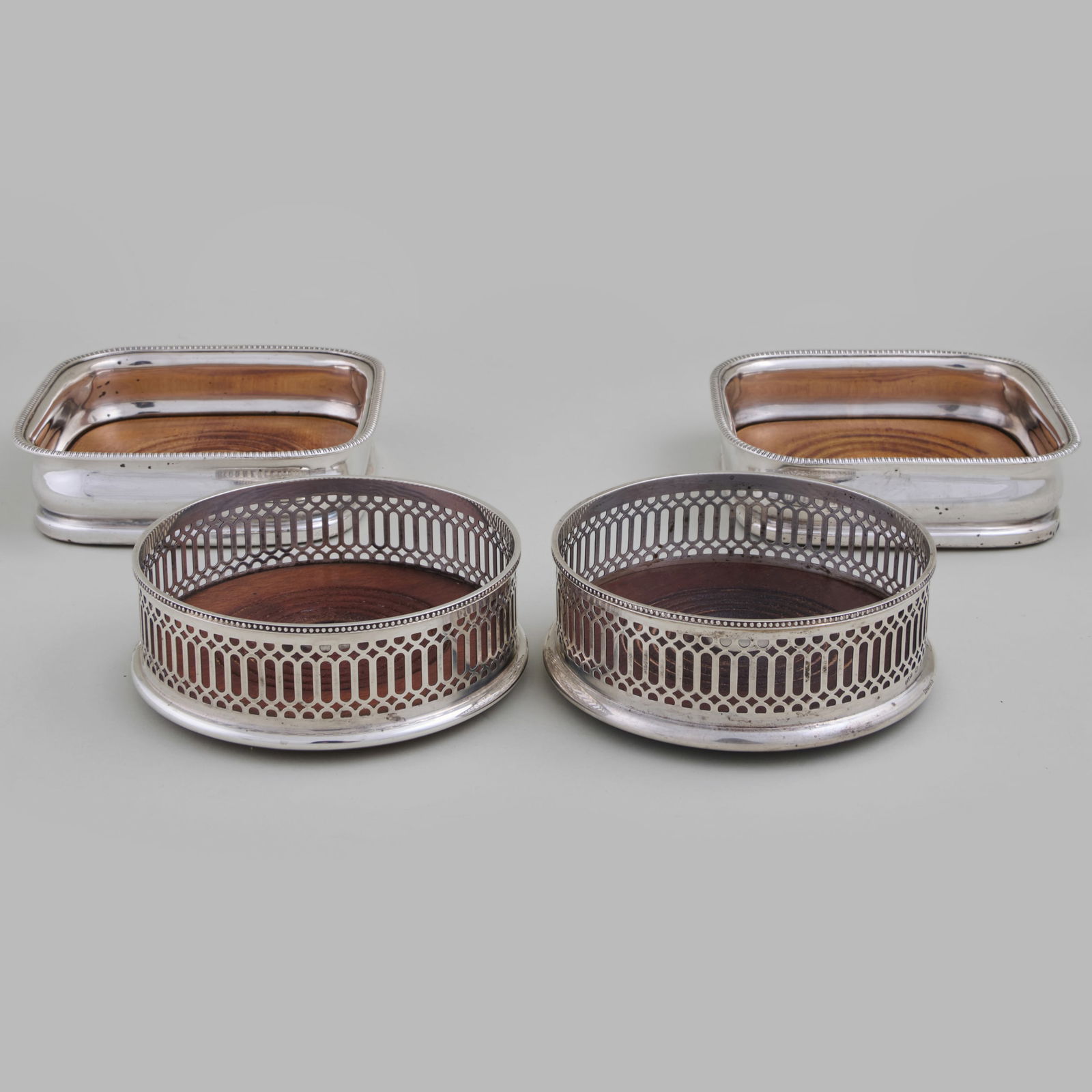 Pair of Tiffany & Co. Silver Bottle Coasters and a Pair of Silver Plate Bottle Coasters: Pair of Tiffany & Co. Silver Bottle Coasters and a Pair of Silver Plate Bottle Coasters The silver with pierced galleries, marked 'Sterling'; the silver plate are shaped squares. The silver 1 1/2 x 5