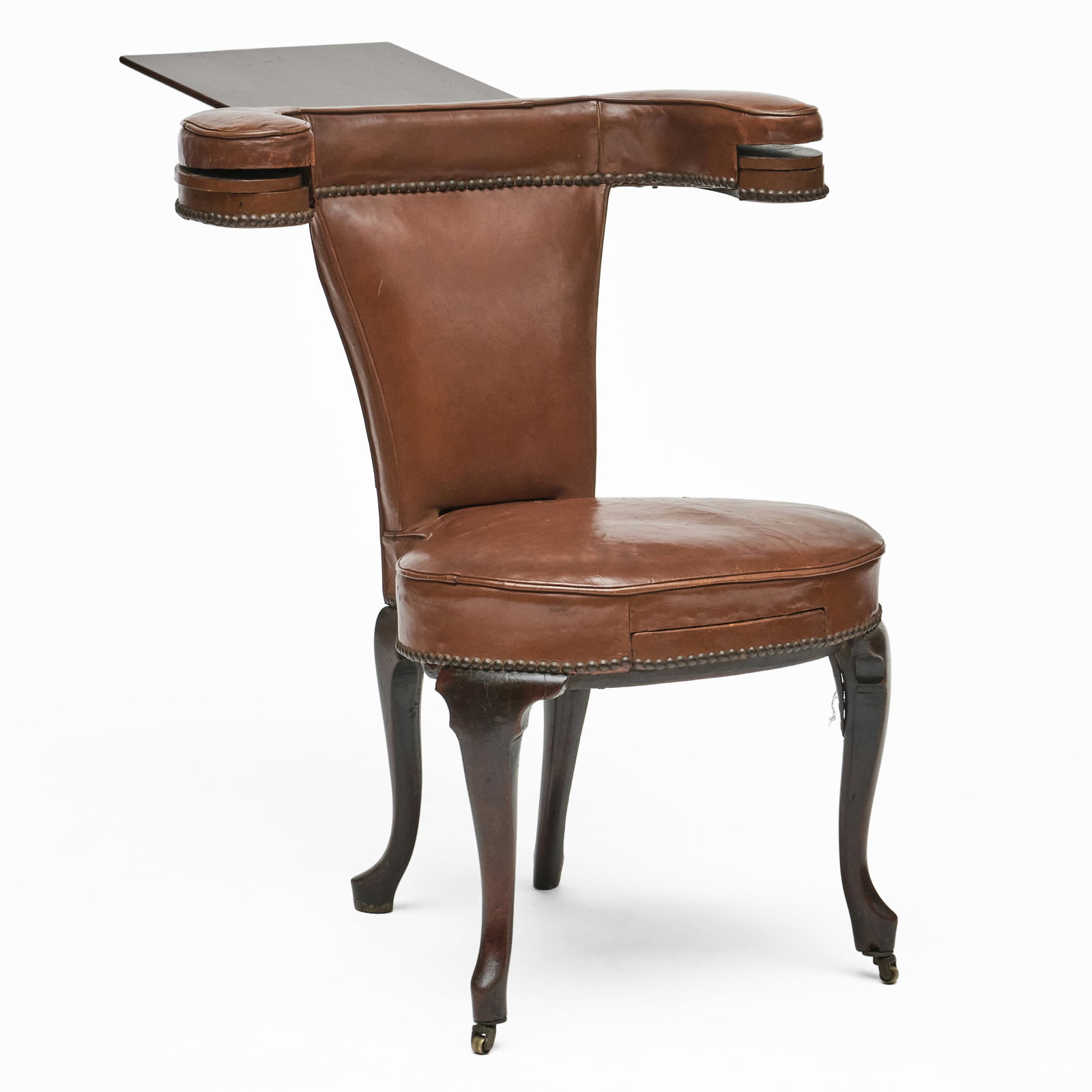 George III Mahogany and Leather Cock Fighting Chair: Fitted with gaming wells and a ratchet mechanism reading/gaming stand, raised on casters on the front legs.34 1/2 x 28 x 25 1/2 in., seat height 18 1/2 in.