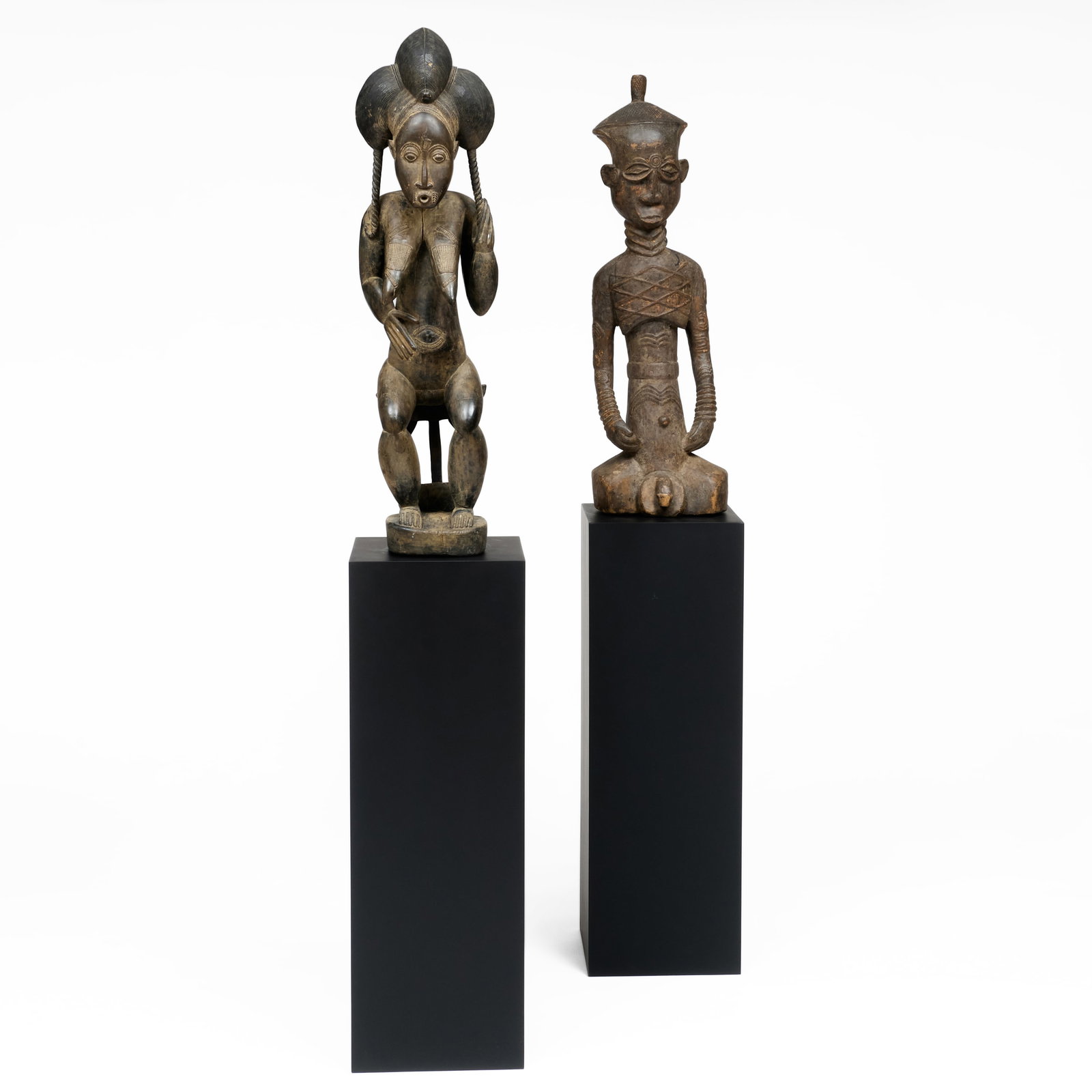 Two African Carved Wood Figures on Ebonized Stands: Total height 6 ft. 1 in.The female figure, 36 1/2 x 8 x 9 in. The male figure, 34 1/2 x 11 x 9 in.
