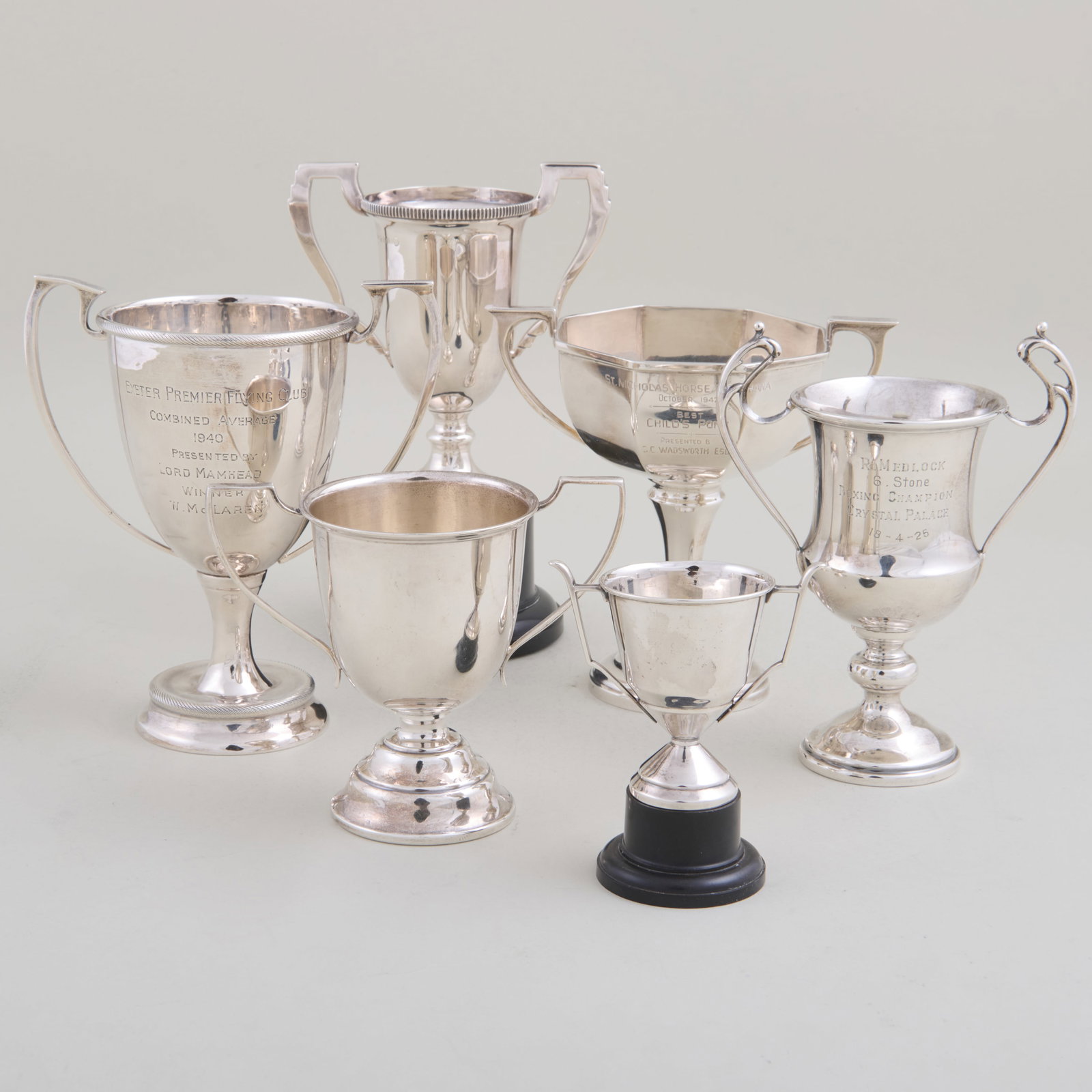 Group of Six English Silver Trophies: Comprising:A child's pony trophy, marked BirminghamTwo trophies on wood stand, marked BirminghamA trophy, marked ExeterA boxing trophy, marked BirminghamA flying club trophy, marked LondonThe largest
