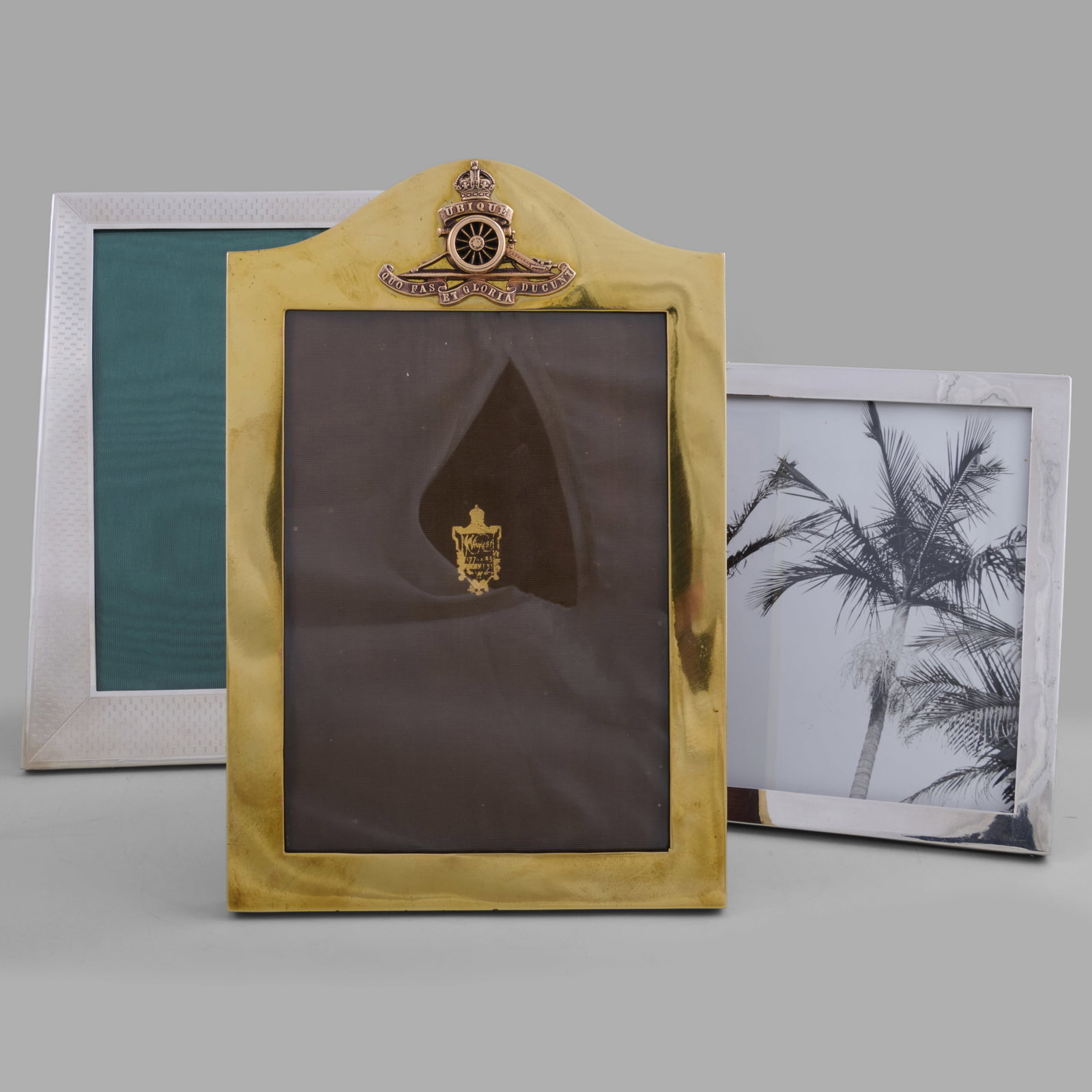 Two George V Silver Frames and a Brass Royal Artillery Frame: Two George V Silver Frames and a Brass Royal Artillery Frame The silver comprising:A rectangular frame, mark of Sanders & Mackenzie, Birmingham, 1919A trapezoidal frame, mark of Fred H. Adams,