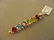 2070: 14K GOLD GARNET, TOPAZ, ETC. INCHWORM PIN