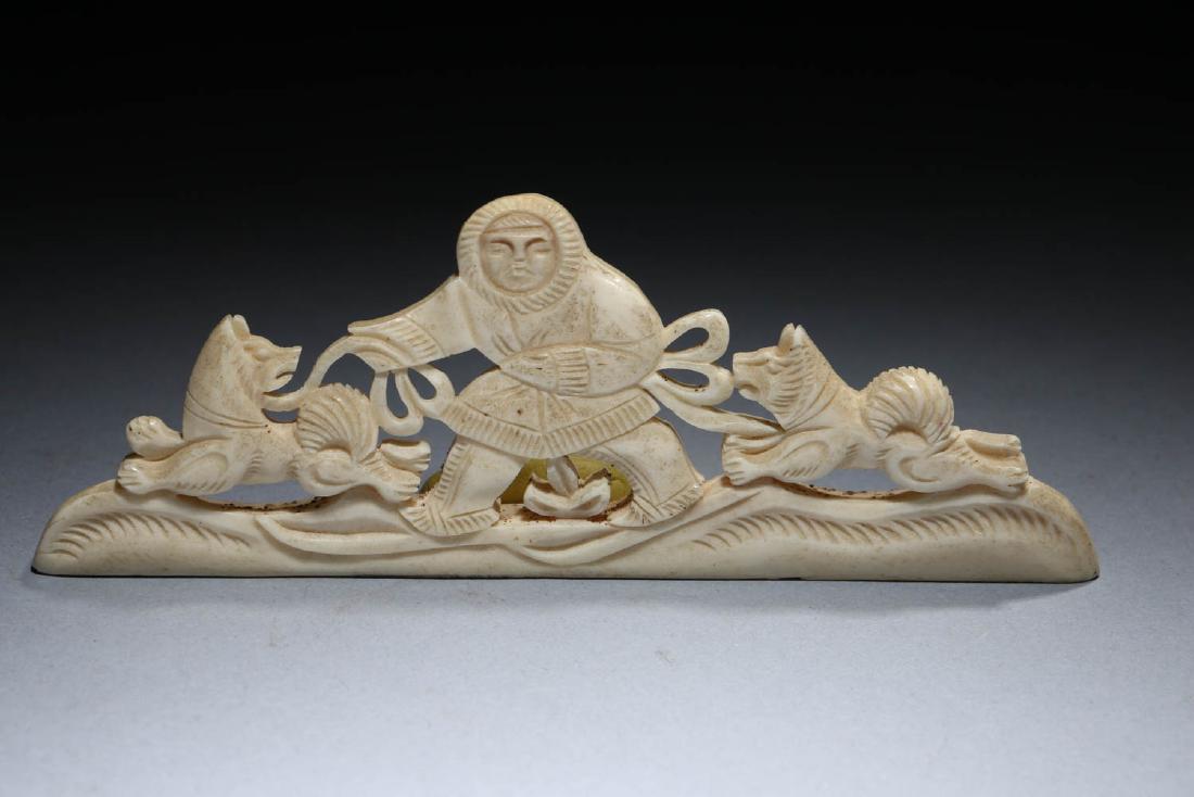 Inuit Carved Walrus Tusk: A beautifully carved walrus tusk depicting a winter scene of a person on skis with two dogs on leashes. Dimensions: 4-1/4" l x 1-1/2" H Note: This lot has a reserve. Reserve must be met to win the lot