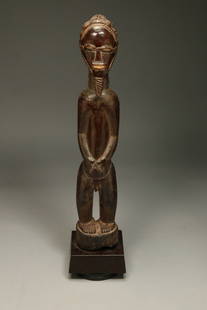 African Art Baule Statue: A wood male figure statue with beard, long braided hair, arms at side, hands on stomach. 14_1-2" H. Display stand is included. Provenance: Ex Holland collection