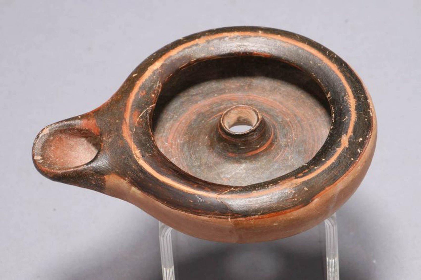 Ancient Oil Lamp: An Ancient Greek oil lamp with hole in center. 3--3/4" L Provenance: Ex. Private collection, NYC