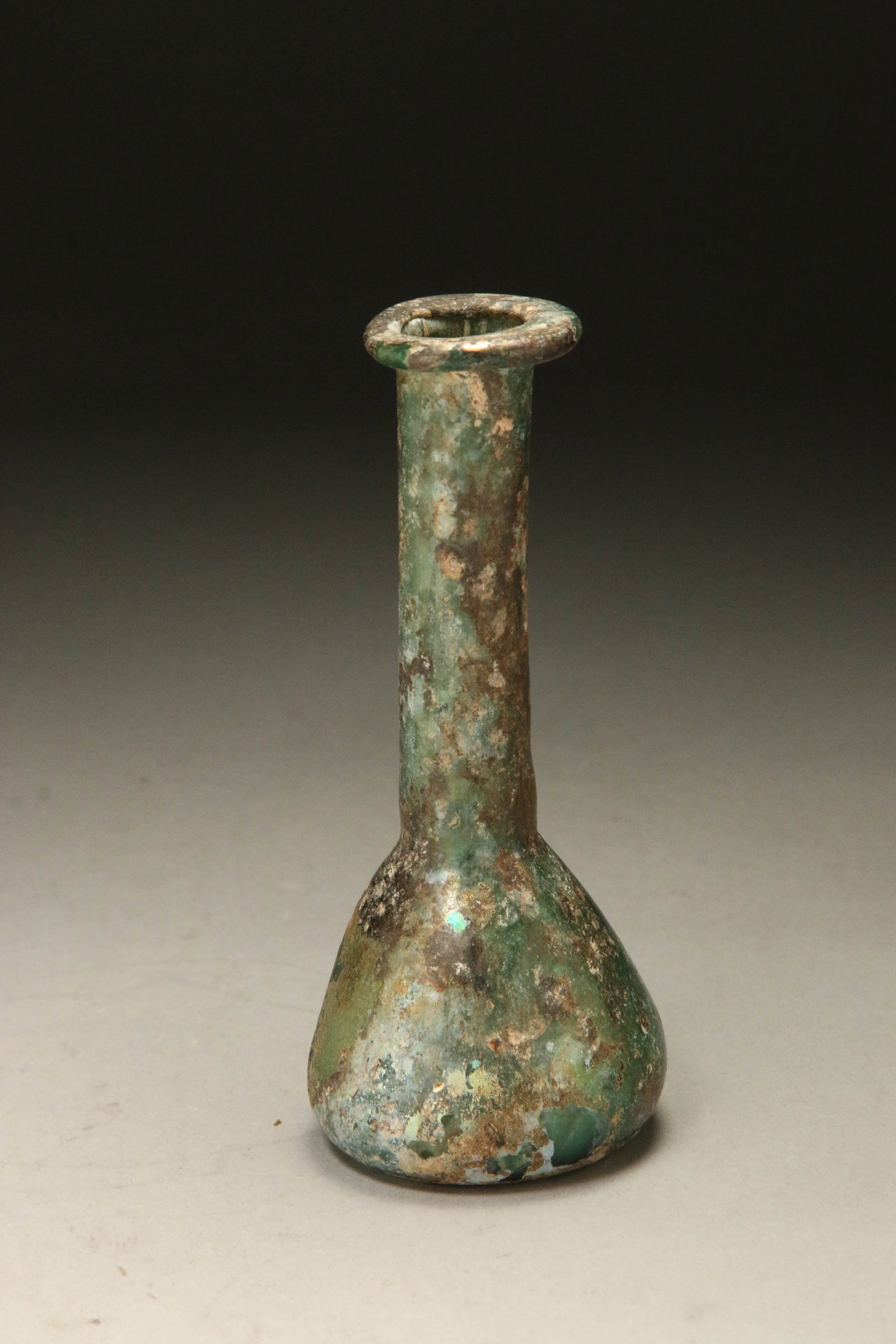 Ancient Roman Glass Unguentarium: An ancient Roman glass bottle with great iridescent, bulbous body sitting on flat bottom, flared neck and rimmed mouth.