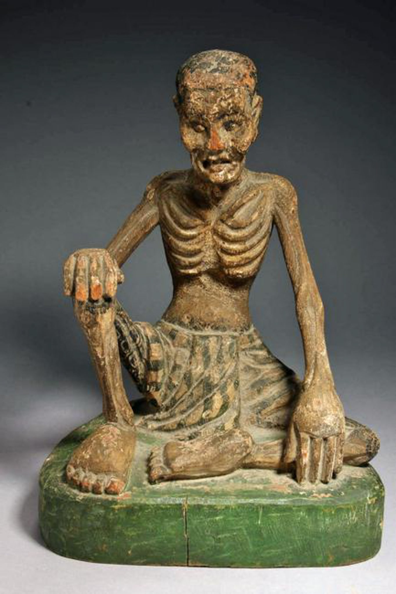 Southeast Asia Ascetic Figure: A wood carving of a seating emaciated man with tattooed legs. 19th century. 11 H ". Provenance: Ex. Private collection, L. Stewart.``