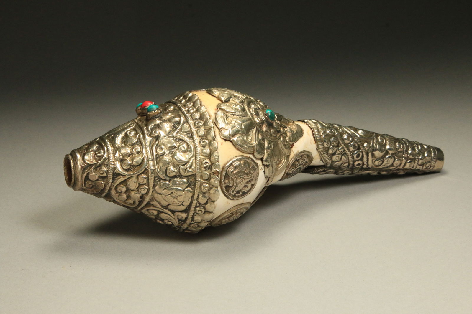 Tibetan Conch Shell Horn: A conch shell horn with silver and coral, turquoise inlay. 10" L. The Tibetan conch shell horn, also known as the "Dung-dkar", is a traditional ritual instrument used in Tibetan Buddhism The ceremonia
