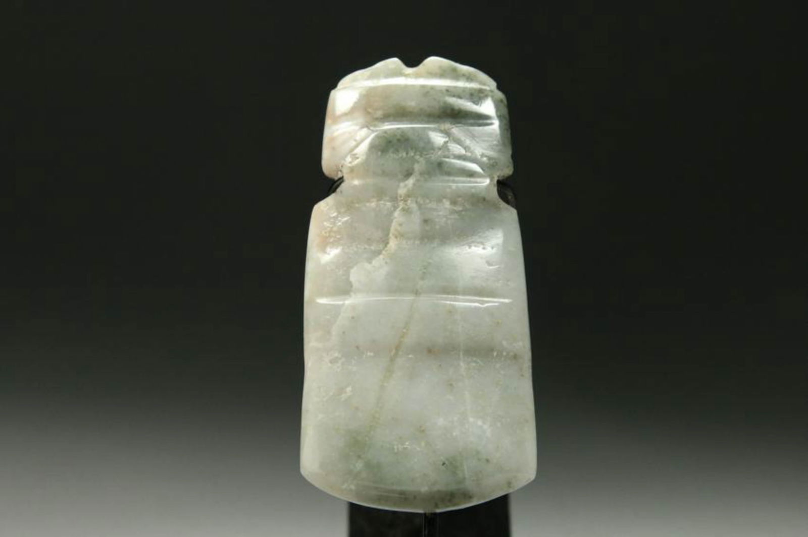 Pre-Columbian Jadeite Stone Celt Figure: A blue-green jadeite stone celt with arms at chest, simple carved facial features, suspension holes. Display stand included. 4-3/8" H Provenance: Ex Midwest collection.