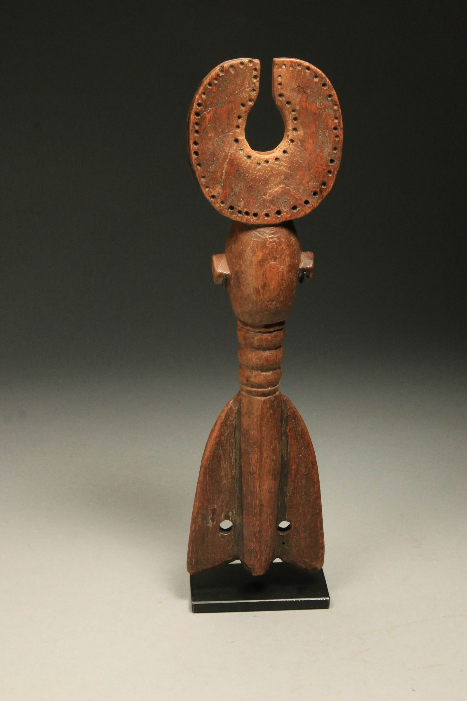 African Art Mossi Whistle - Burkina Faso: A wood Mossi whistle with crescent top, ribbed body and winged bottom with suspension holes. Display stand is included. 11" H. Provenance: Thomas Wheelock