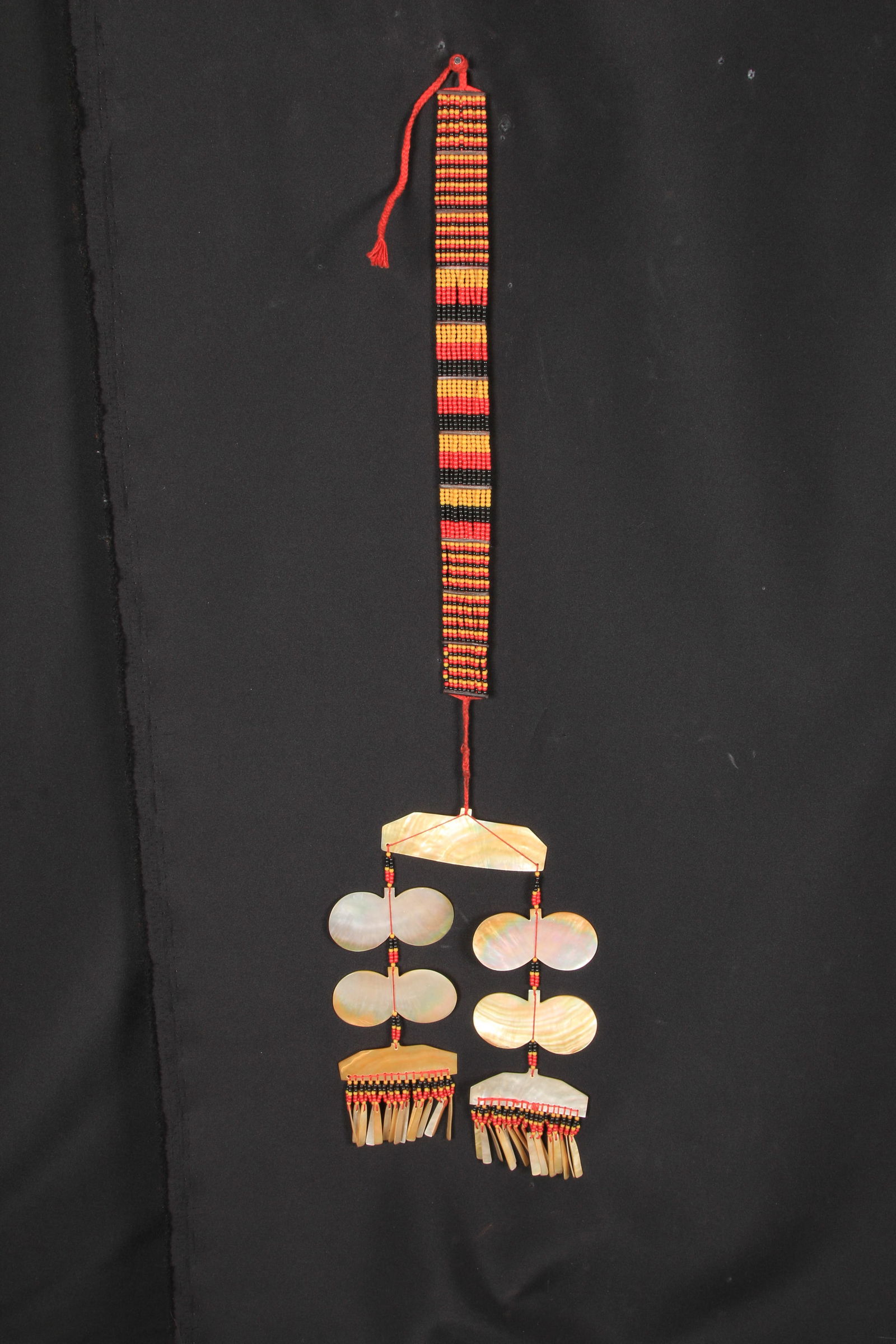 Philippines Sipatttal Chest Ornament: A Sipattal chest ornament, Isneg people, Northern Luzon. Mother of pearl butterfly shaped pendants, with mother of pearl dangles suspended from yellow, orange and black beads collar. 27" L. The sipatt
