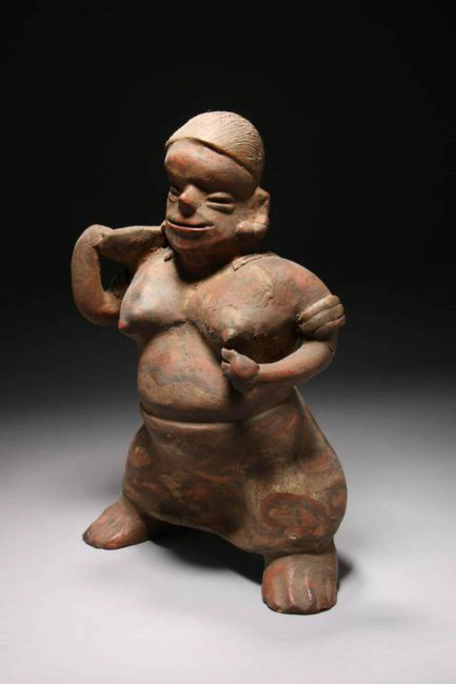 Pre-Columbian Nayarit Figure: A large terracotta figure of a skirted female holding a bowl on her shoulder. 12" h x 8" W