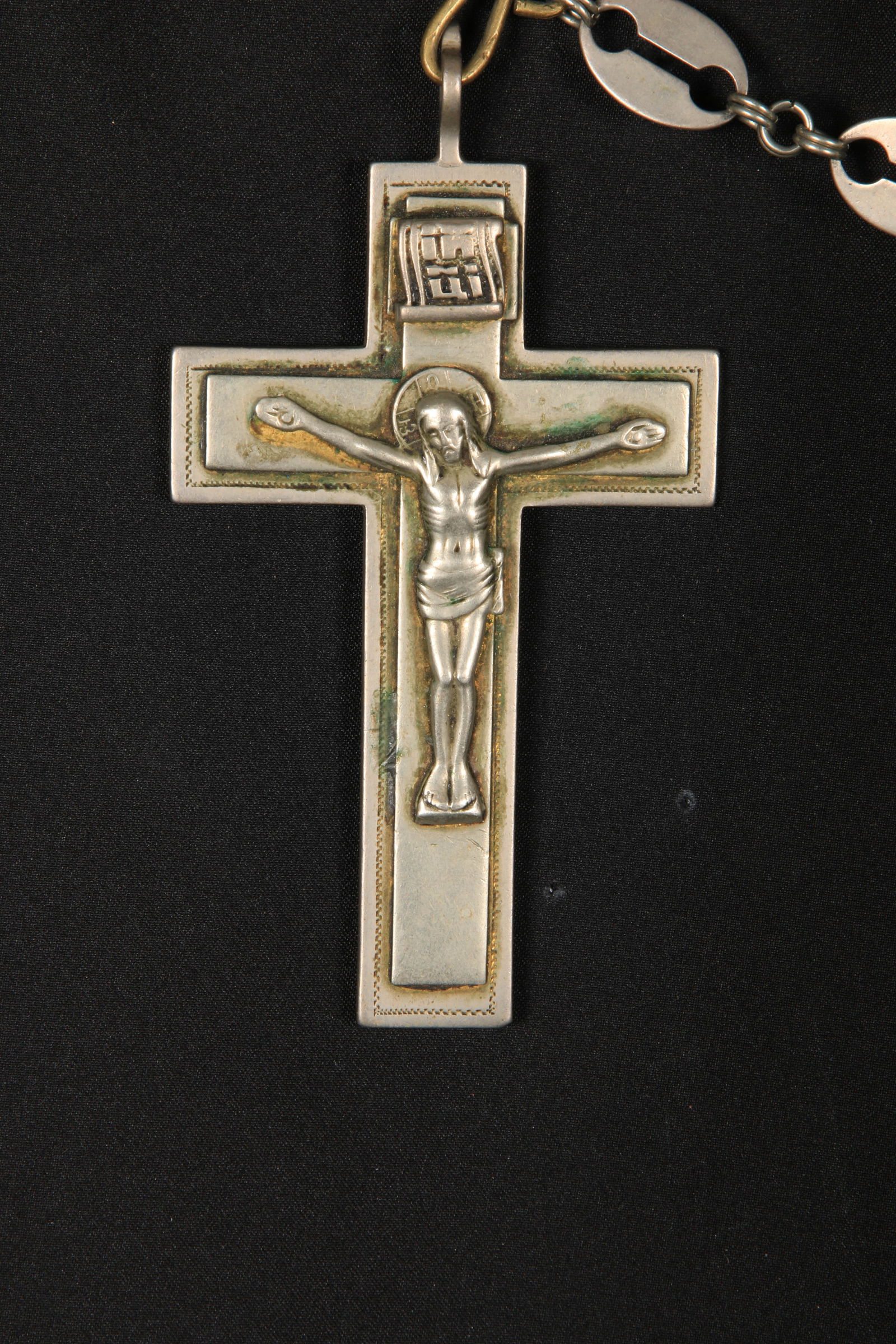 Russian Orthodox Cross: A white metal pectoral cross with chain. The cross depicts the cruxification of Jesus Christ with a halo at his head, the Cyrillic letters of IHUI "King of Glory" at top of his head. The inscription o